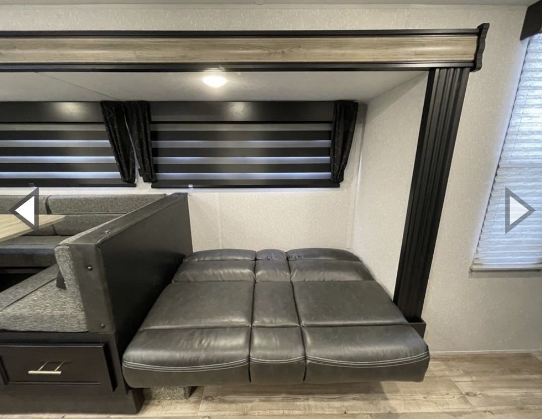 RV rental interior: Versatile dinette with table and benches, next to a fold-out sofa bed, maximizing compact living space.. Forest River Cherokee Grey Wolf 2021