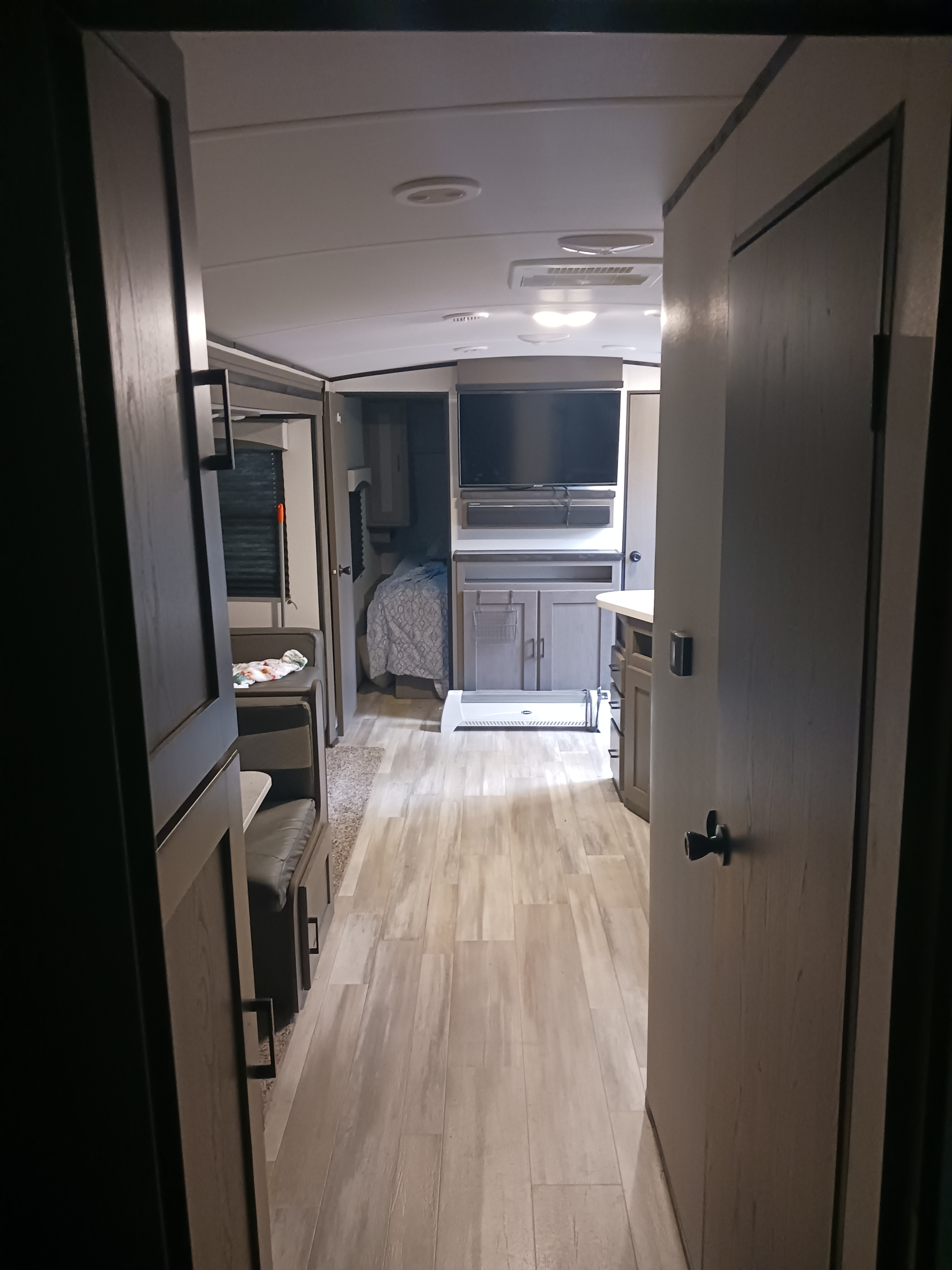 View down the aisle of an RV rental showing the living area, kitchen, and bedroom beyond.. Embrace EL310 2021