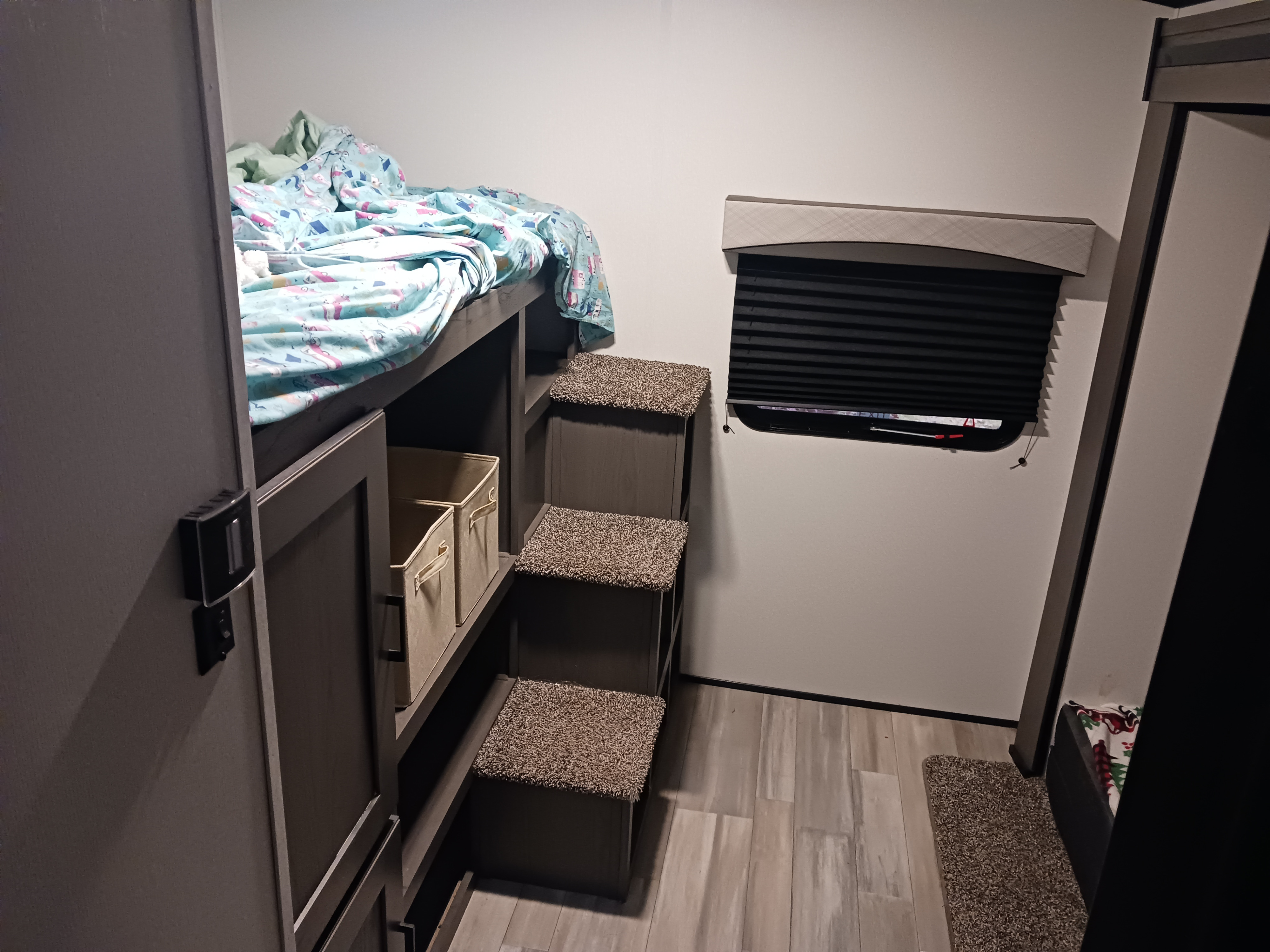 An RV rental's bunk bed area, complete with built-in steps, storage bins, and a window, offering a compact and functional space.. Embrace EL310 2021