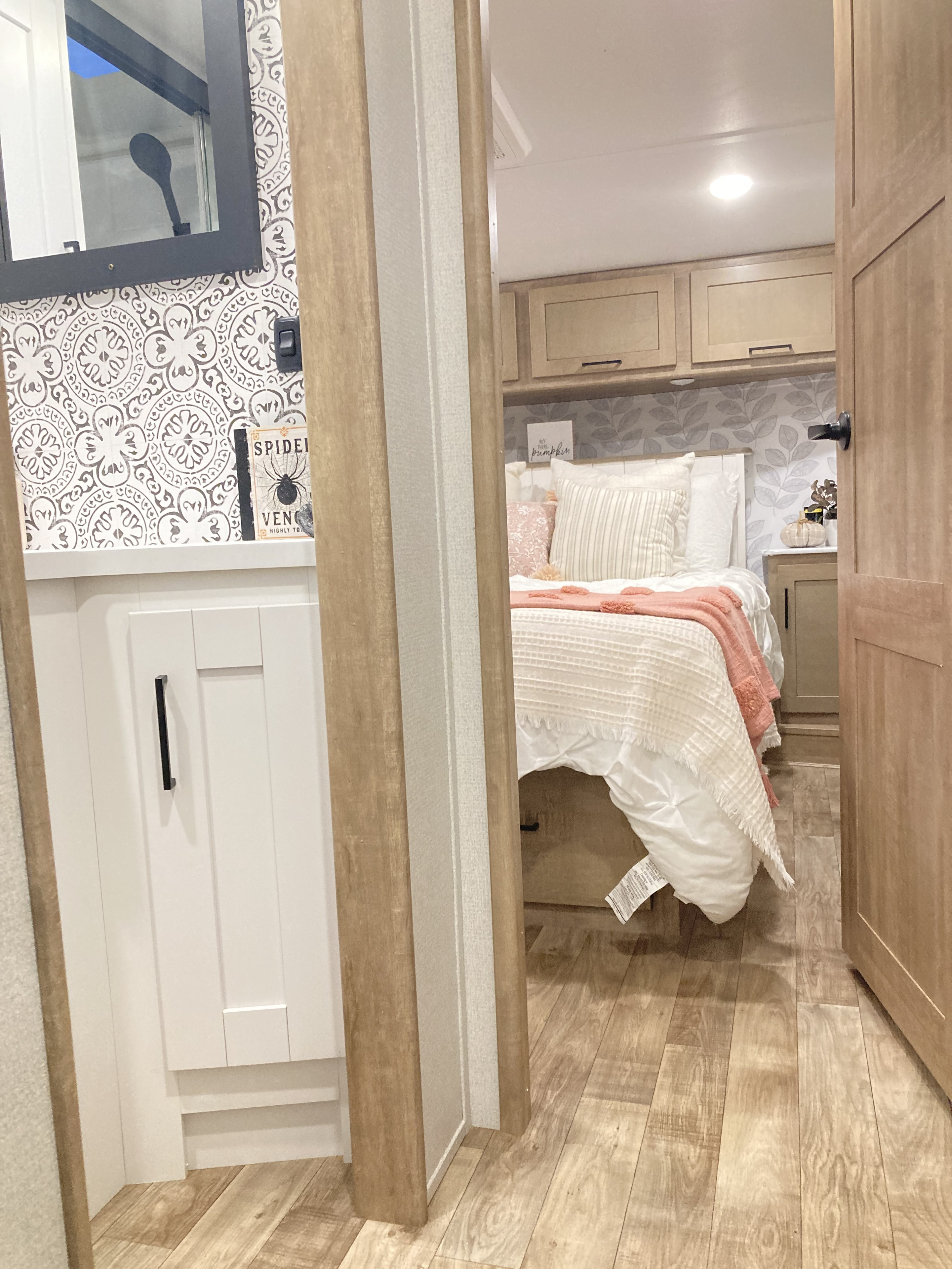 Experience a comfortable RV rental with a stylish bedroom featuring soft bedding, light wood cabinets, and modern bathroom access.. Keystone RV Arcadia 2022