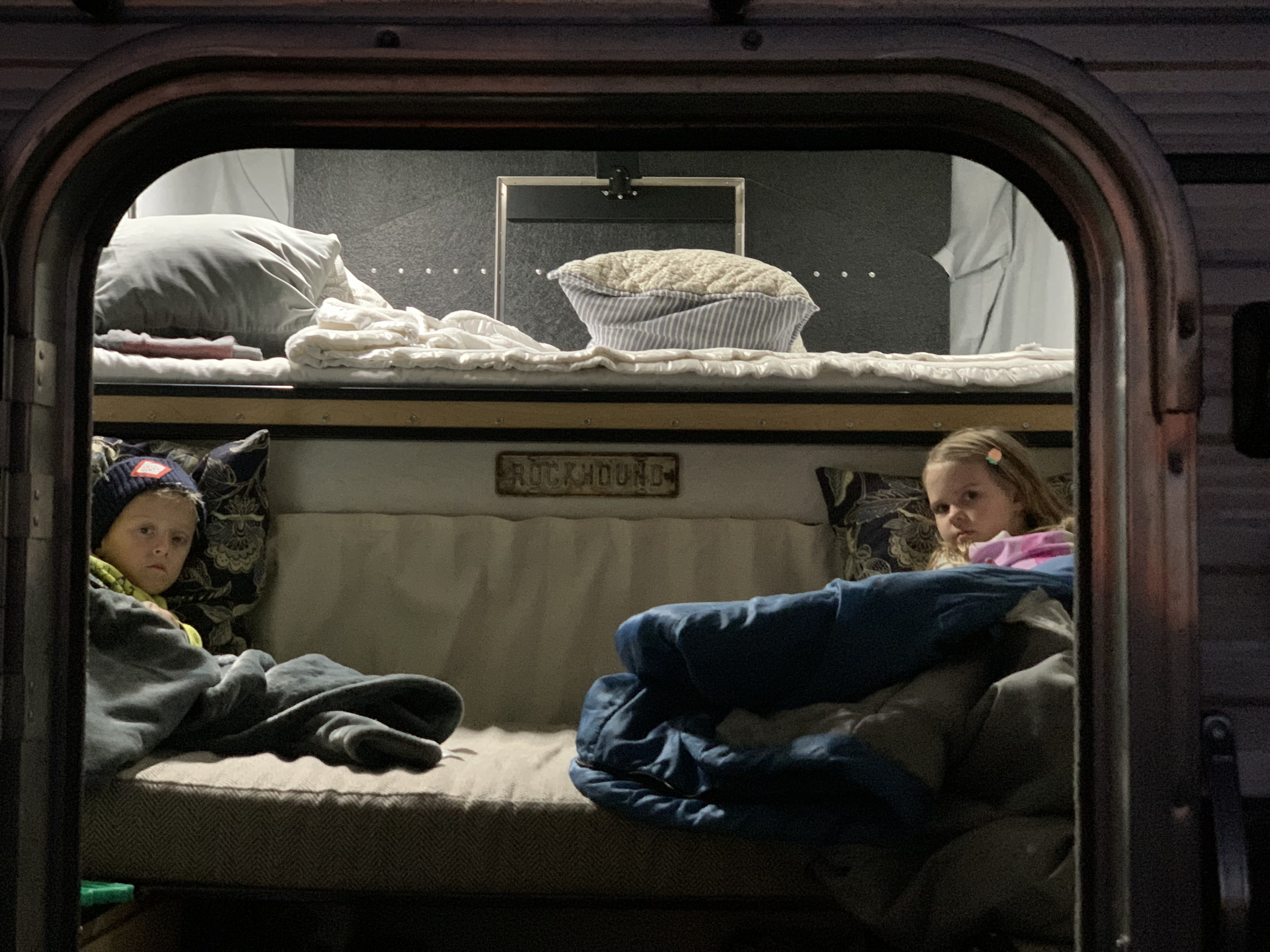 Two kids cozy in their RV rental bunk beds, ready for a good night's sleep on family adventures.. Four Wheel Campers Fleet 2021