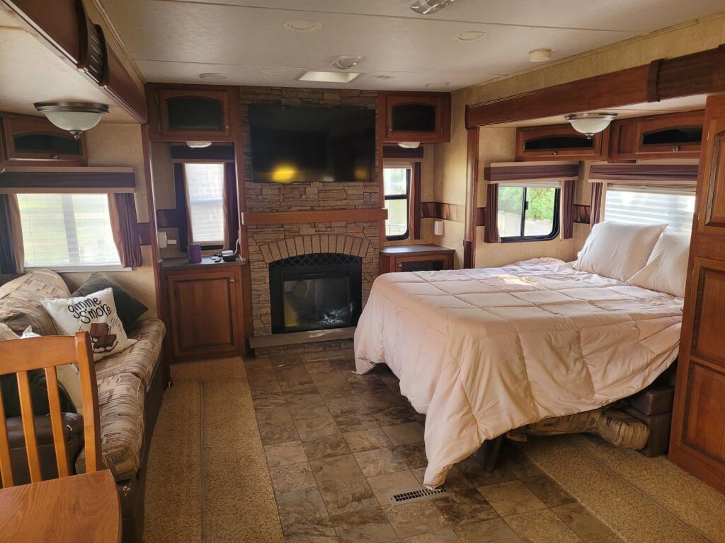 Inside a comfy RV rental: large bed, sofa, and a stone fireplace with TV. Perfect for glamping.. Jayco Eagle 2012