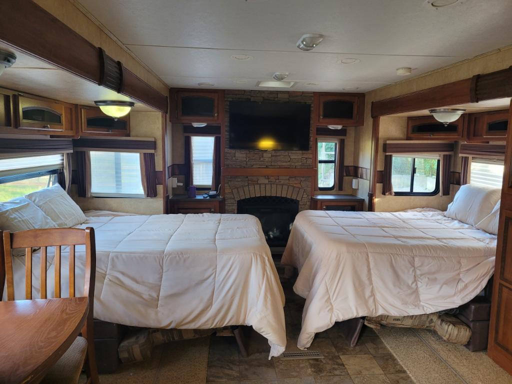 Spacious RV rental interior featuring two comfortable beds, a fireplace, and ample living area space for a cozy stay.. Jayco Eagle 2012