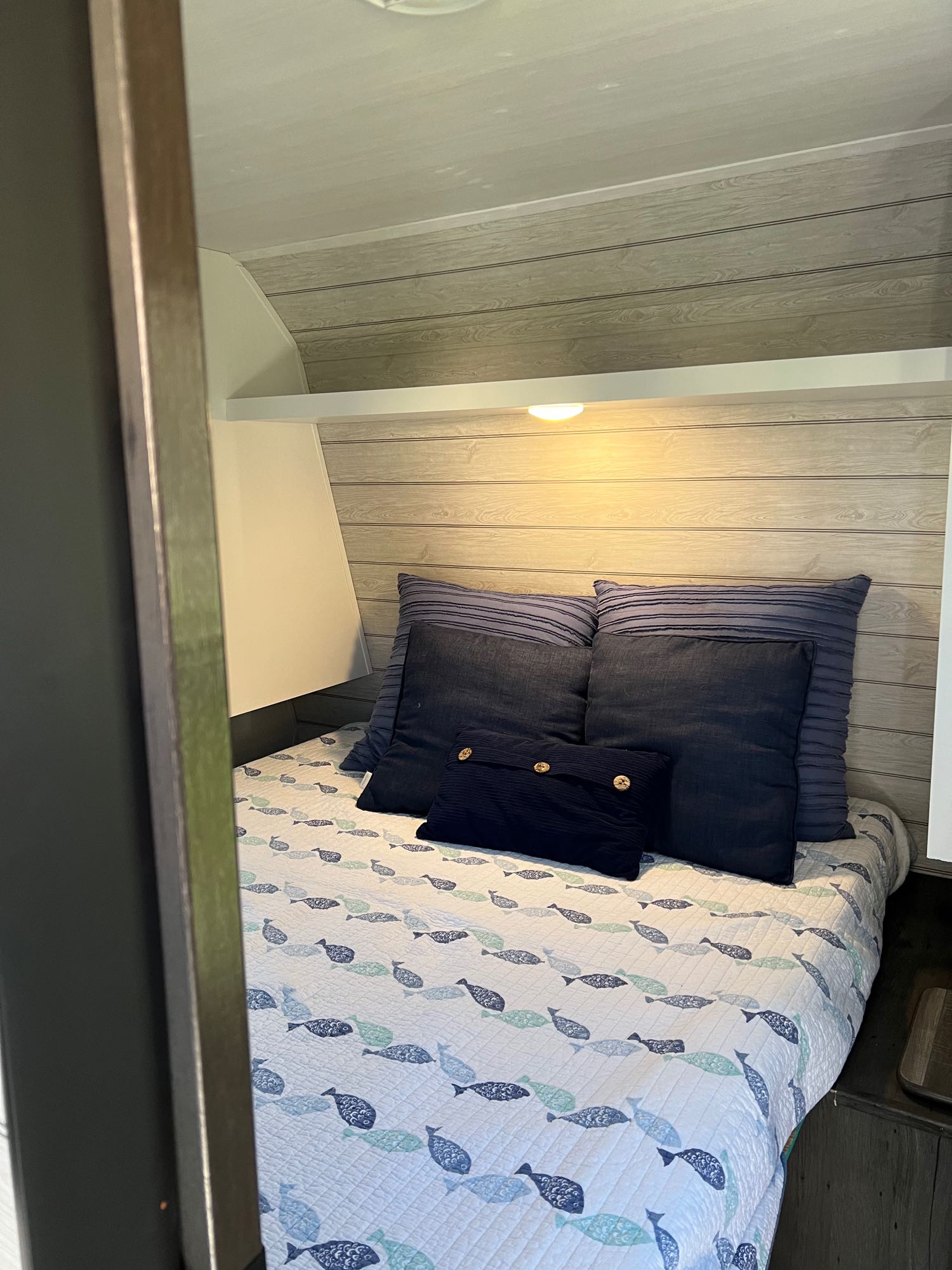 Cozy RV rental bedroom with wood paneling, blue pillows, and fish-patterned comforter. Perfect for travel.. Keystone RV Hideout 2023