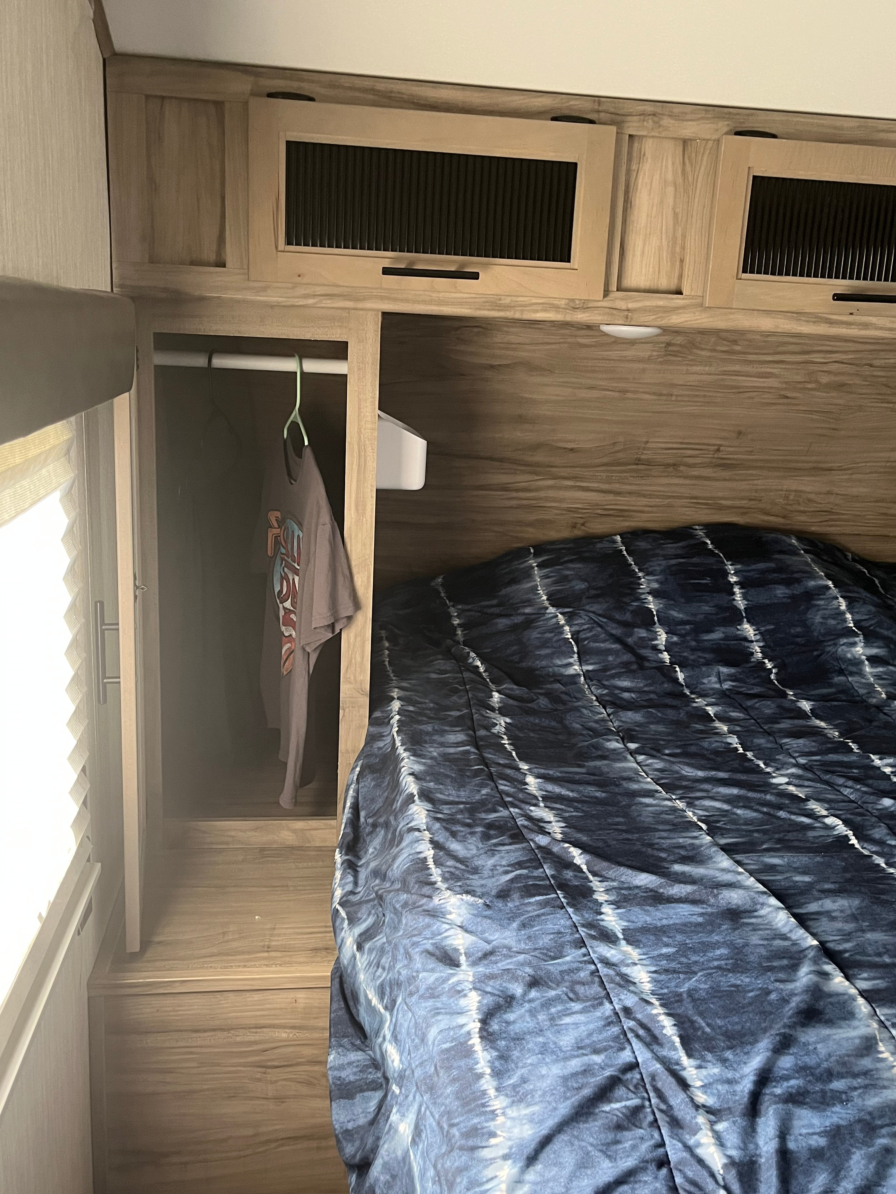 Cozy RV rental bedroom: bed with unique comforter, overhead cabinets, and small closet space.. Forest River Cherokee Alpha Wolf 2021