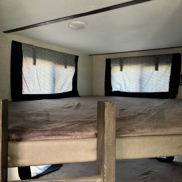 Cozy RV rental bunk bed interior with soft bedding and windows. Ideal for travel.. Keystone RV Bullet Ultra Lite 2019