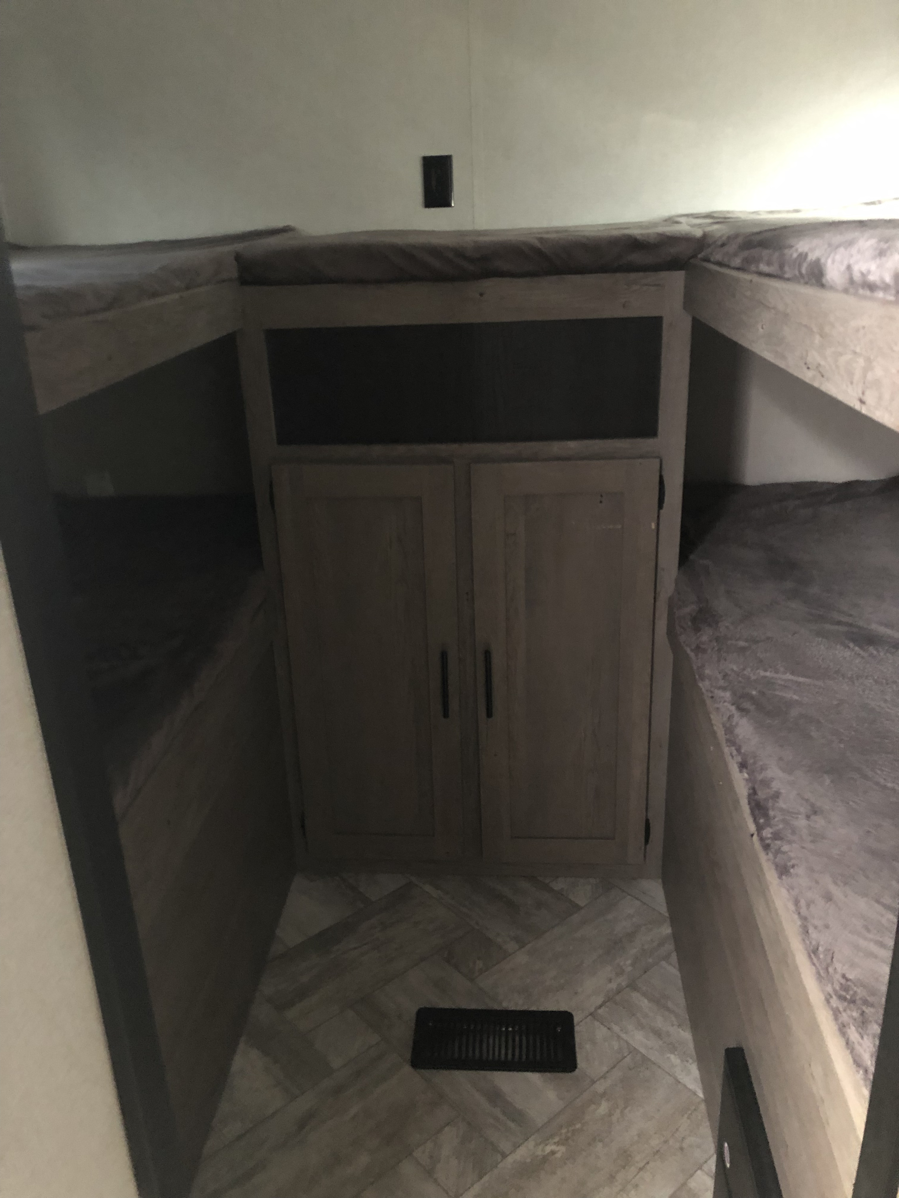 RV rental interior: view of bunk beds on left & right, central cabinet with cubby, and patterned floor.. Springdale 298bh 2021
