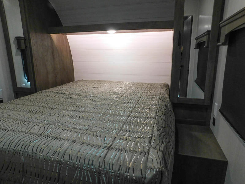 Cozy RV rental bedroom features a comfortable bed, built-in storage, and an overhead reading light. Ideal for travel.. Forest River Shockwave 2022
