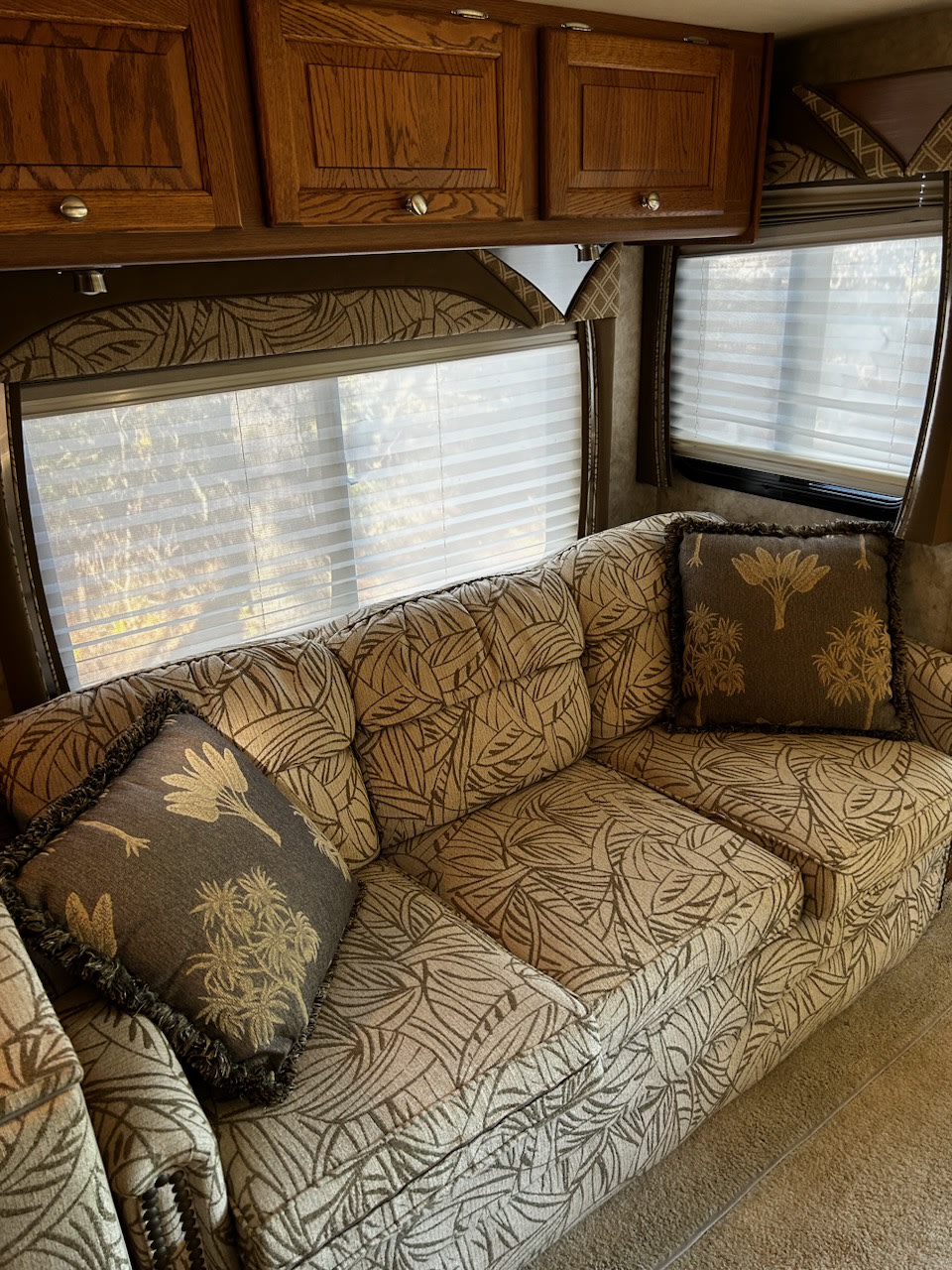 Cozy RV rental interior featuring a patterned couch, wooden cabinets, and bright windows with horizontal blinds.. Allegro Allegro Bay 2006