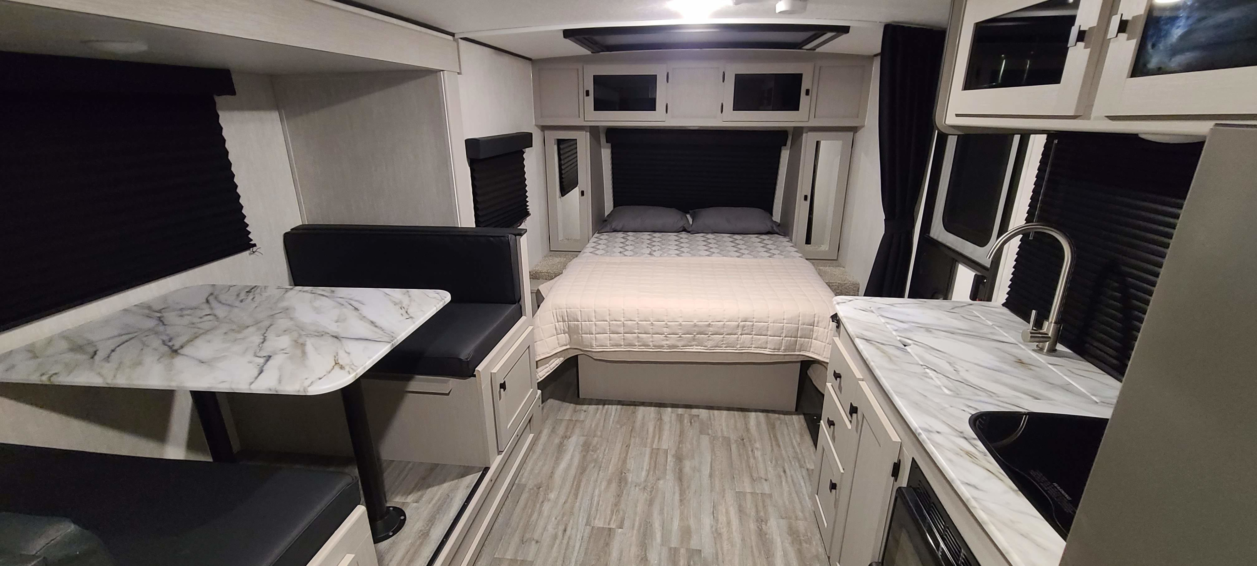Spacious RV rental interior with modern bedroom, dining area, and compact kitchen featuring a sleek sink and counters.. Forest River inc Apex 208 BHS 2024