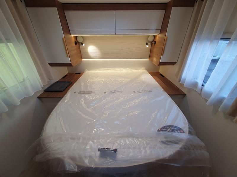 Experience comfort in this RV rental's cozy bedroom. Features a new, plastic-wrapped bed, side shelves, and reading lights.. Pilote G741 EXPRESSION 2024