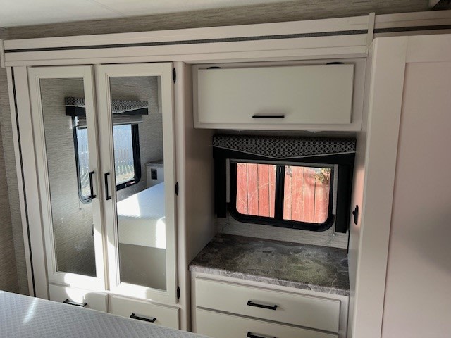 RV rental interior: Mirrored closet, cabinet, window & storage unit. Bright, modern bedroom setup.. Thor Chateau Victory 2022