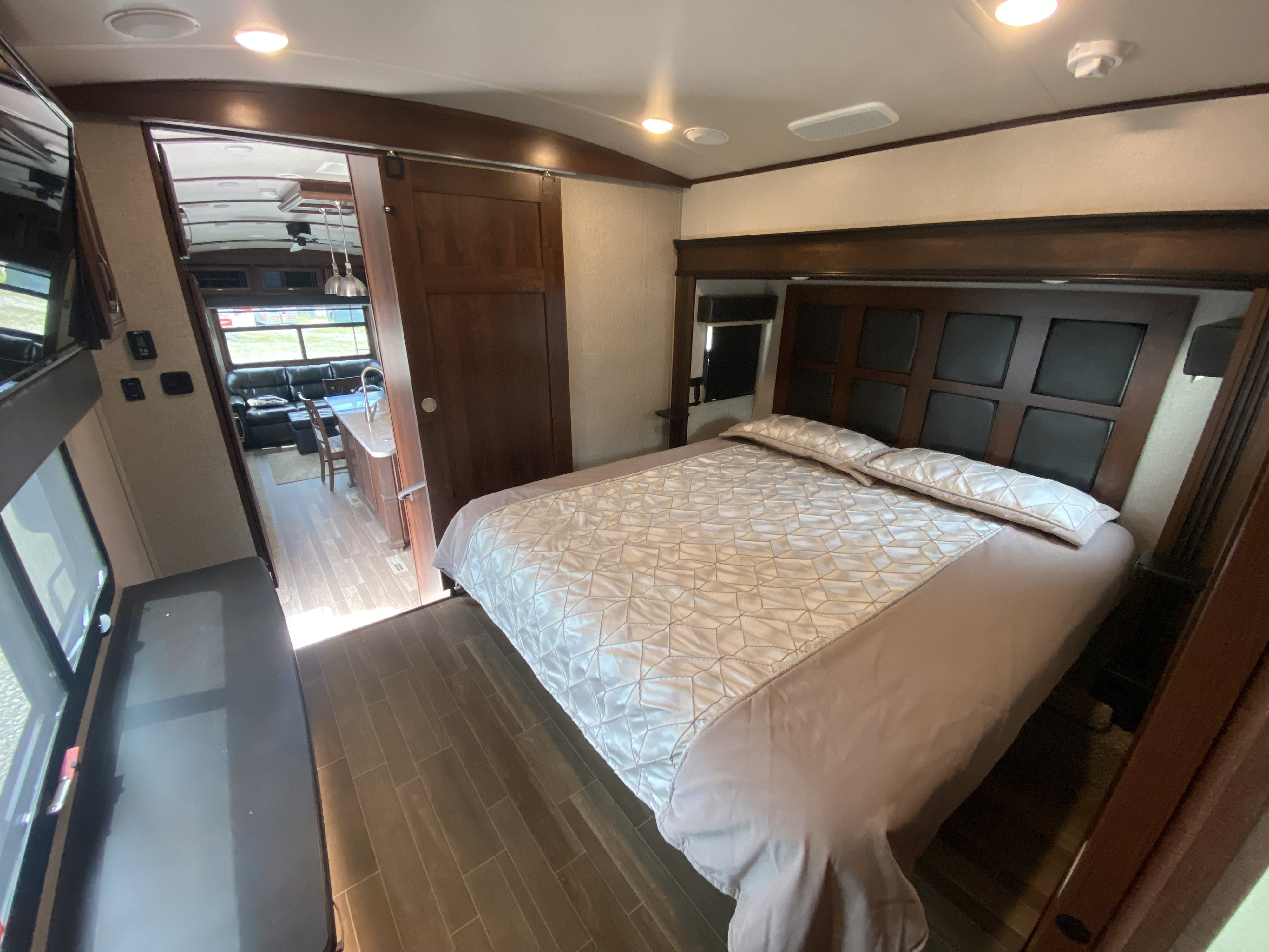 This RV rental features a bright, inviting bedroom with a plush bed, opening to a spacious living area and kitchen.. Jayco Pinnacle 2020