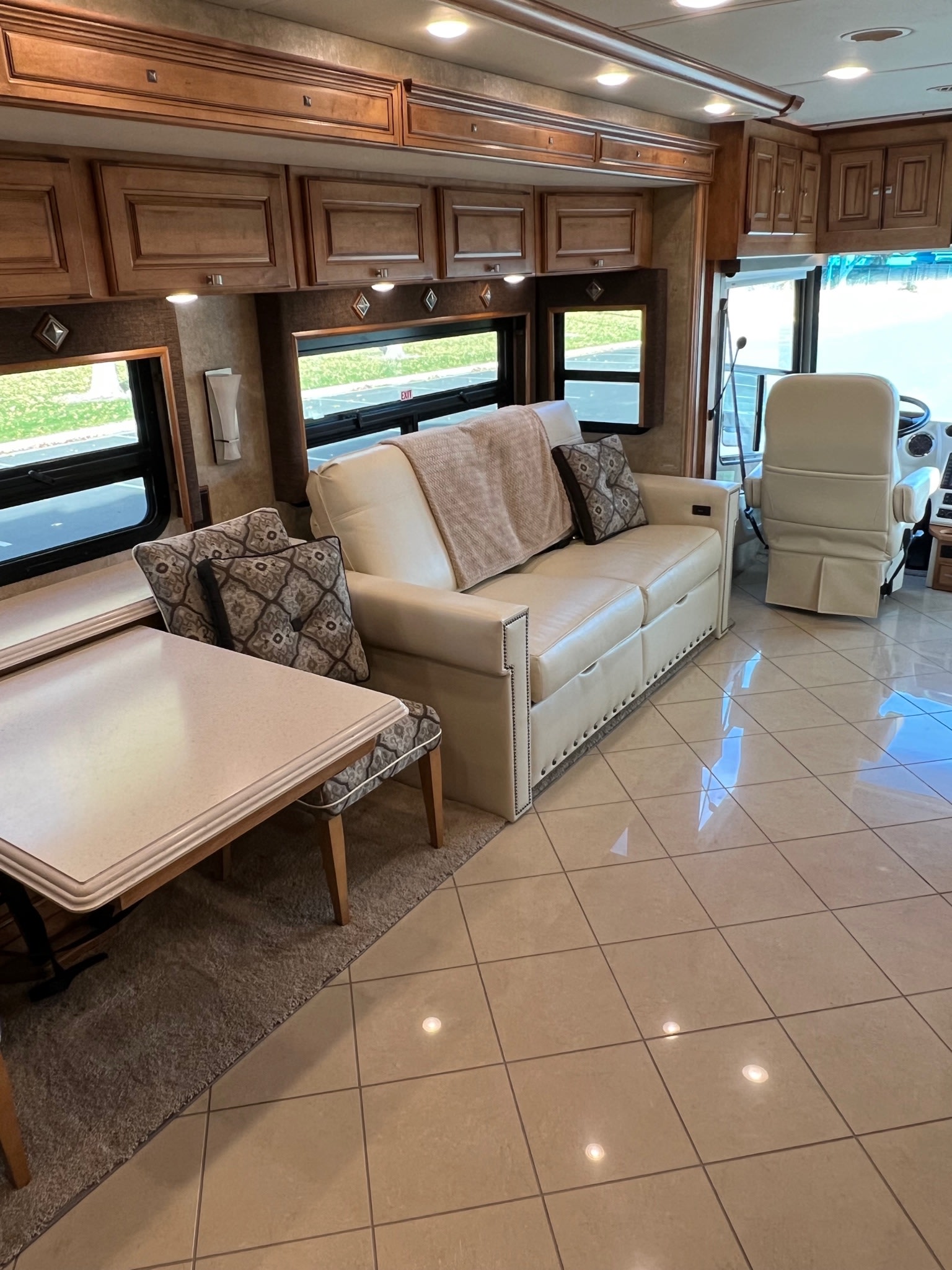 Spacious RV rental interior: cream sofa, dining table, wood cabinetry, and tiled floor, offering luxury comfort.. Itasca Meridian 2014