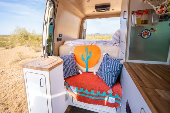 Cozy RV rental interior with desert view. Features a functional kitchenette, comfy seating, and bed for your next adventure.. VanCraft VanCraft Class B 2022