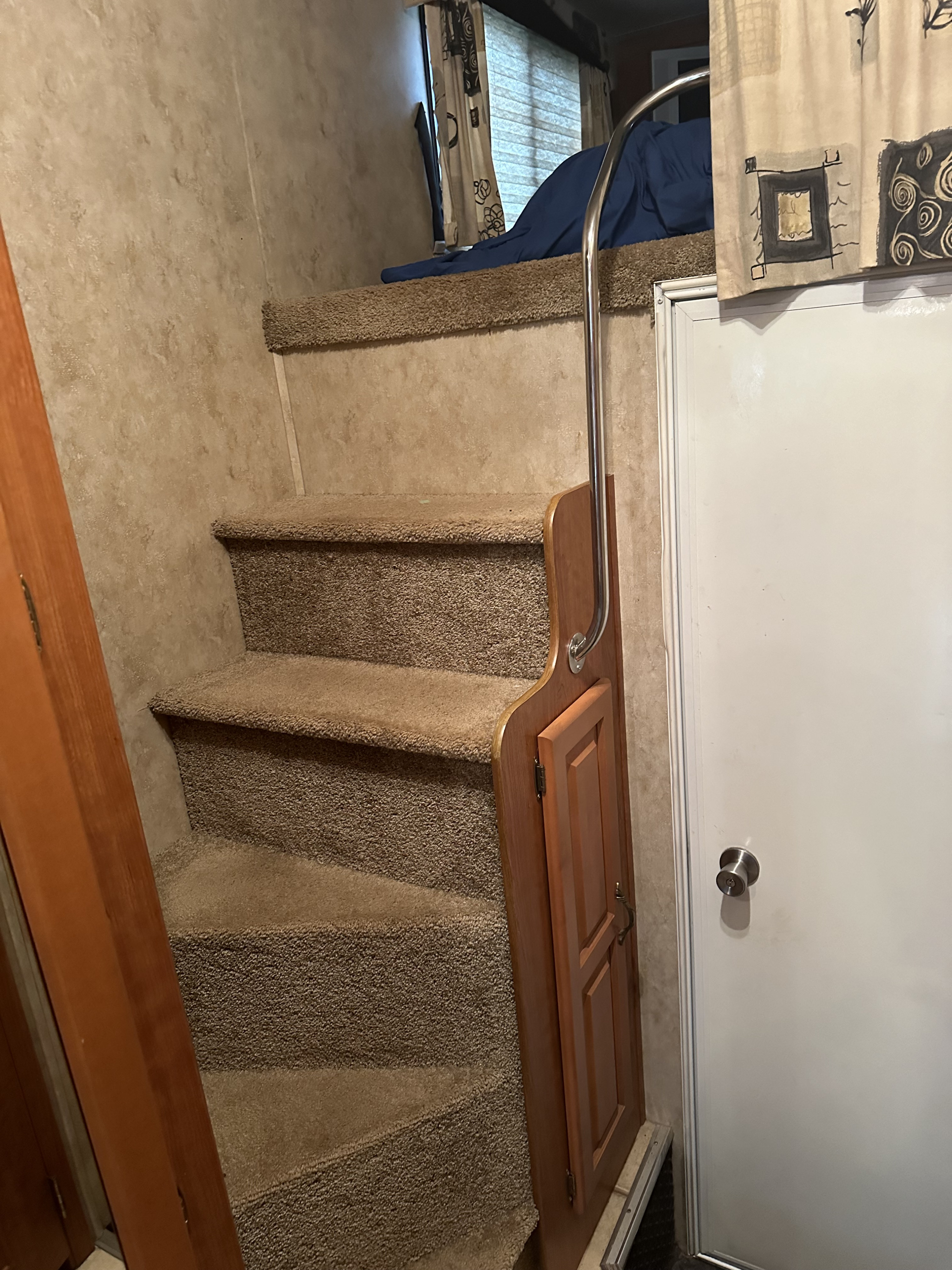 Inside an RV rental, carpeted stairs lead to a cozy bunk bed area, complete with a metal handrail, storage, and a door.. Damon Corporation Outlaw 2007