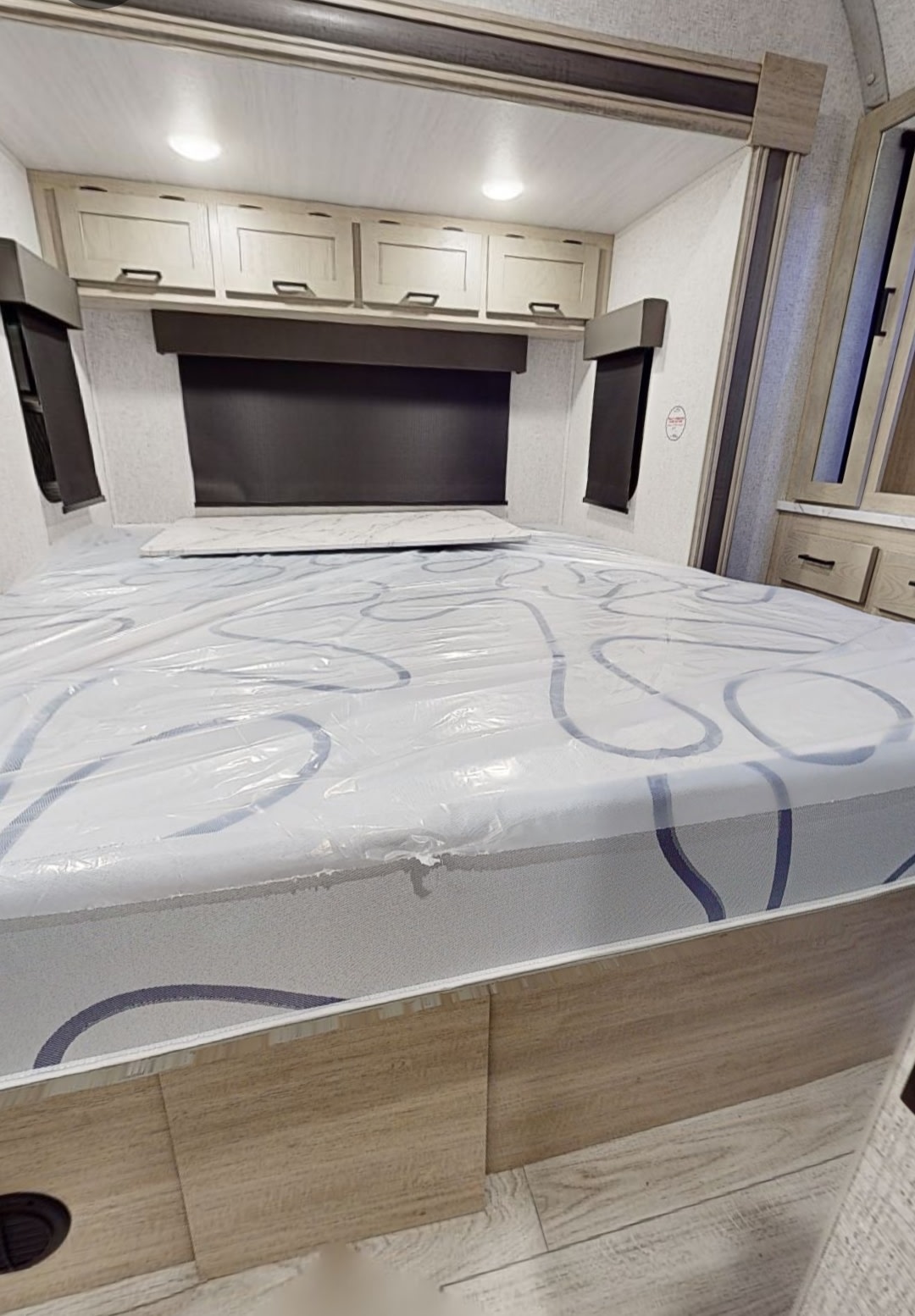 RV rental bedroom: new mattress in plastic, overhead cabinets, windows, and built-in storage make for a cozy space.. East to West Alta 2400KTH 2023