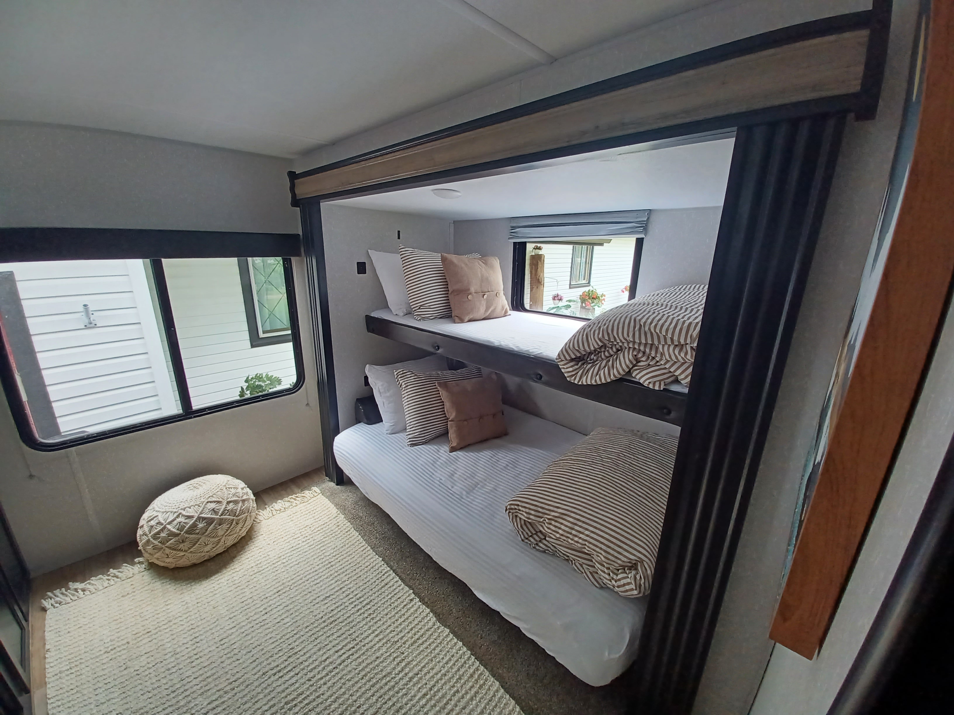 This cozy RV rental bunk room features two comfy beds with striped bedding and a rug, perfect for family adventures.. Forest River Cherokee 2021