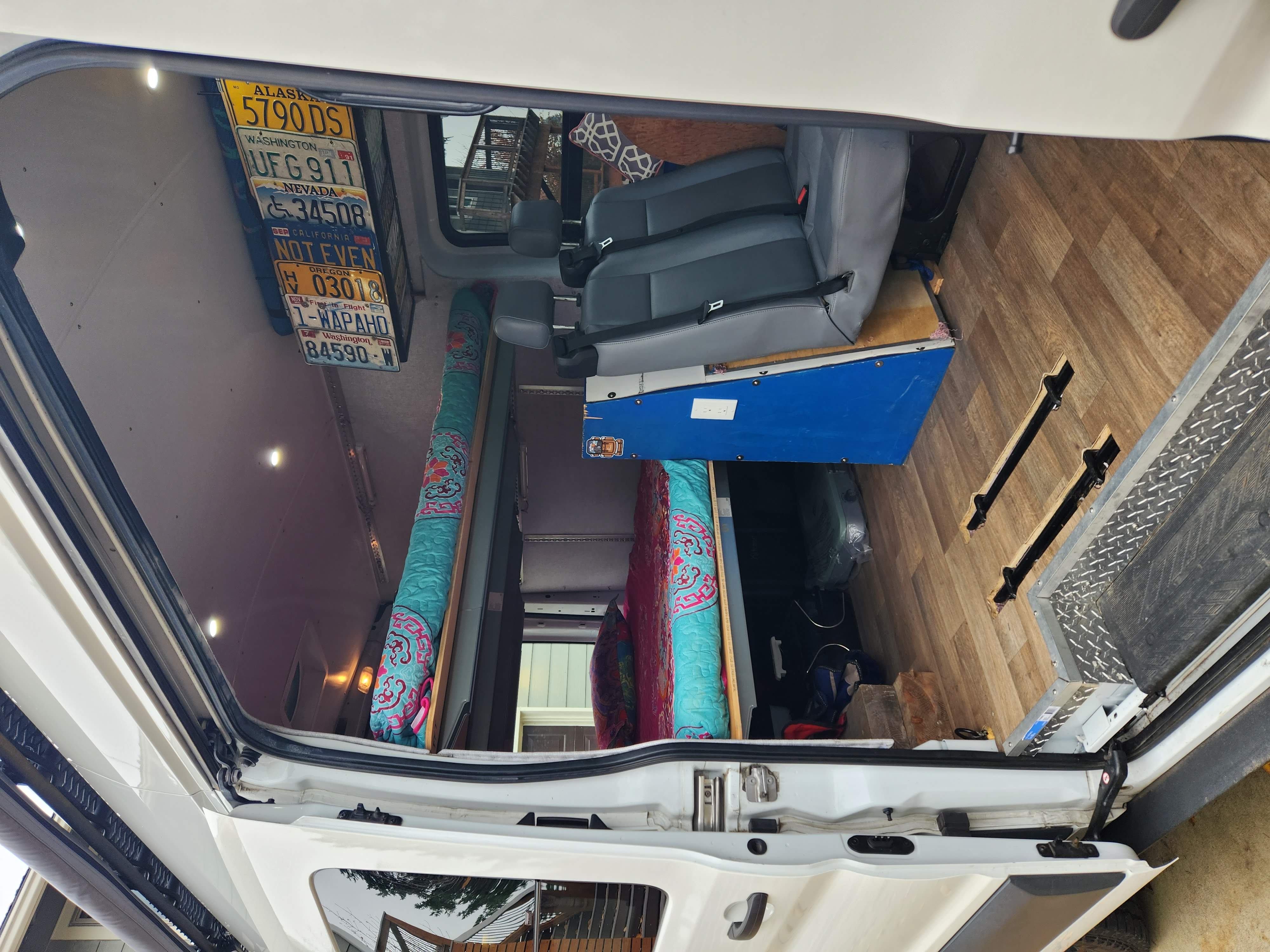 Custom van interior, perfect for an RV rental adventure, with passenger seating, wood floors, & travel mementos.. Ford Transit 2016