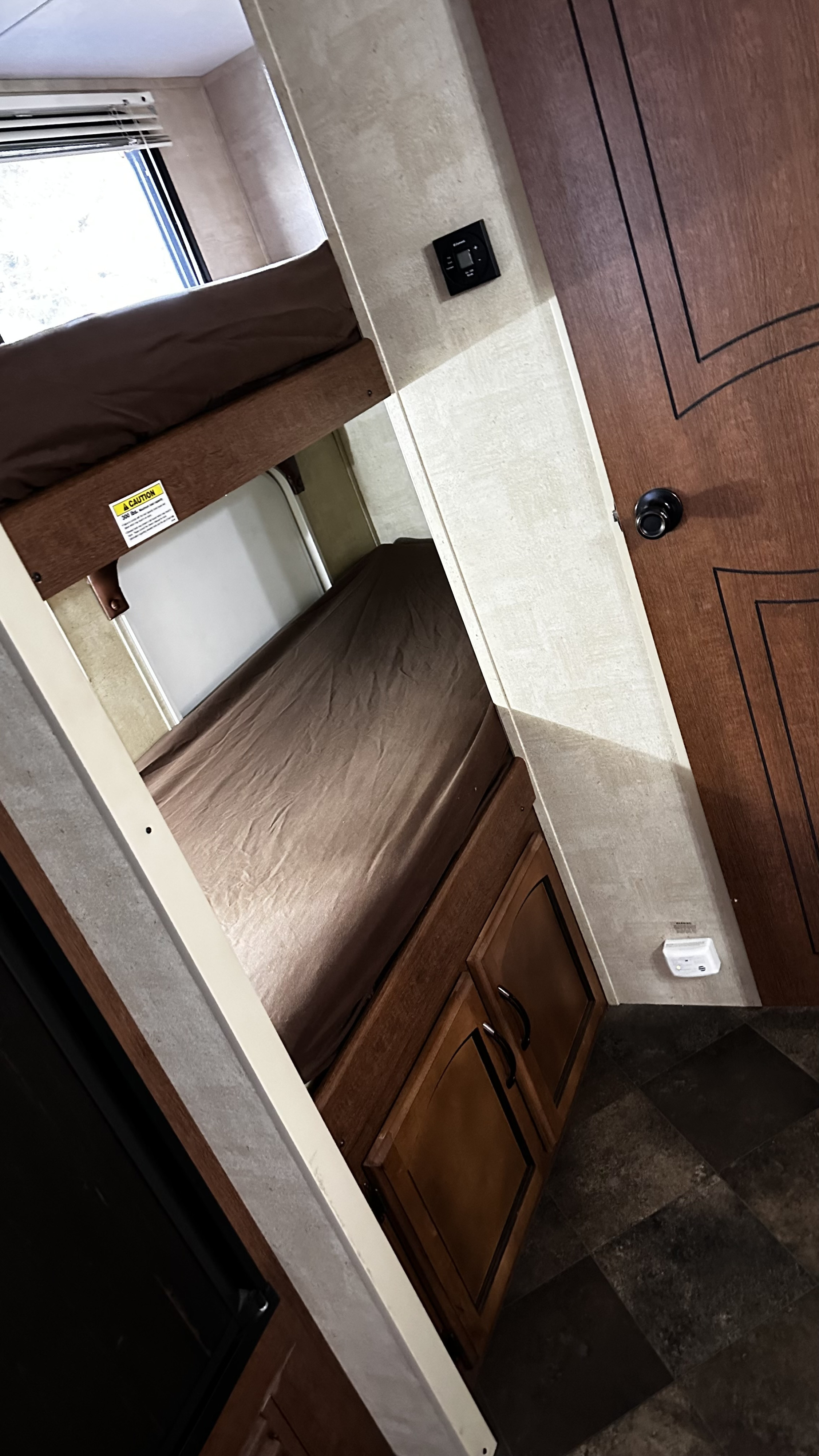 RV rental bunk beds offer compact sleeping. Interior view shows two stacked beds, wall controls, and storage cabinets.. Keystone RV Springdale 2014