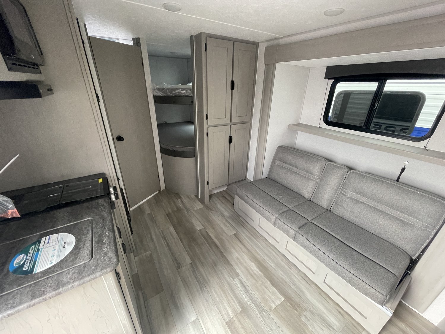 Comfortable RV rental interior with grey sofa, kitchen area, and bunk beds in a modern design.. Coachmen Clipper 2024