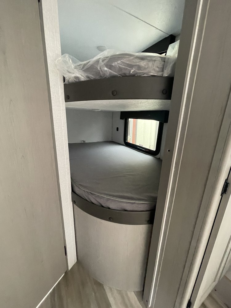 RV rental interior: two bunk beds. The top mattress is in plastic, the lower one is set. This compact sleeping area is ideal for travelers.. Coachmen Clipper 2024