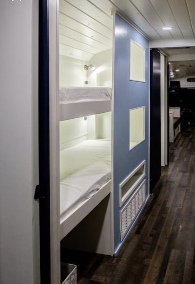 This RV rental offers space-saving built-in bunk beds, with a blue accent wall leading to the main living area.. Thomas Thom 1994