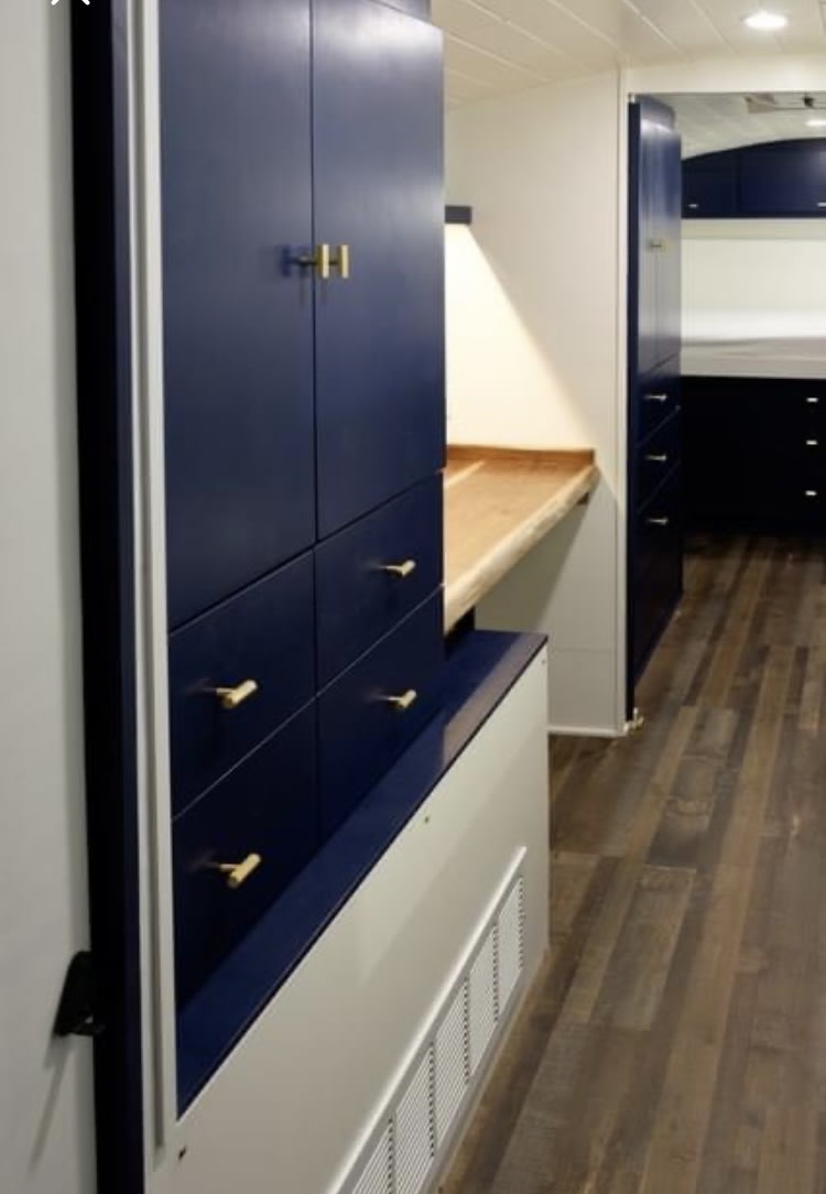 Stylish navy blue cabinets & wood floors in this compact RV rental interior, possibly with bunk beds visible in the back.. Thomas Thom 1994