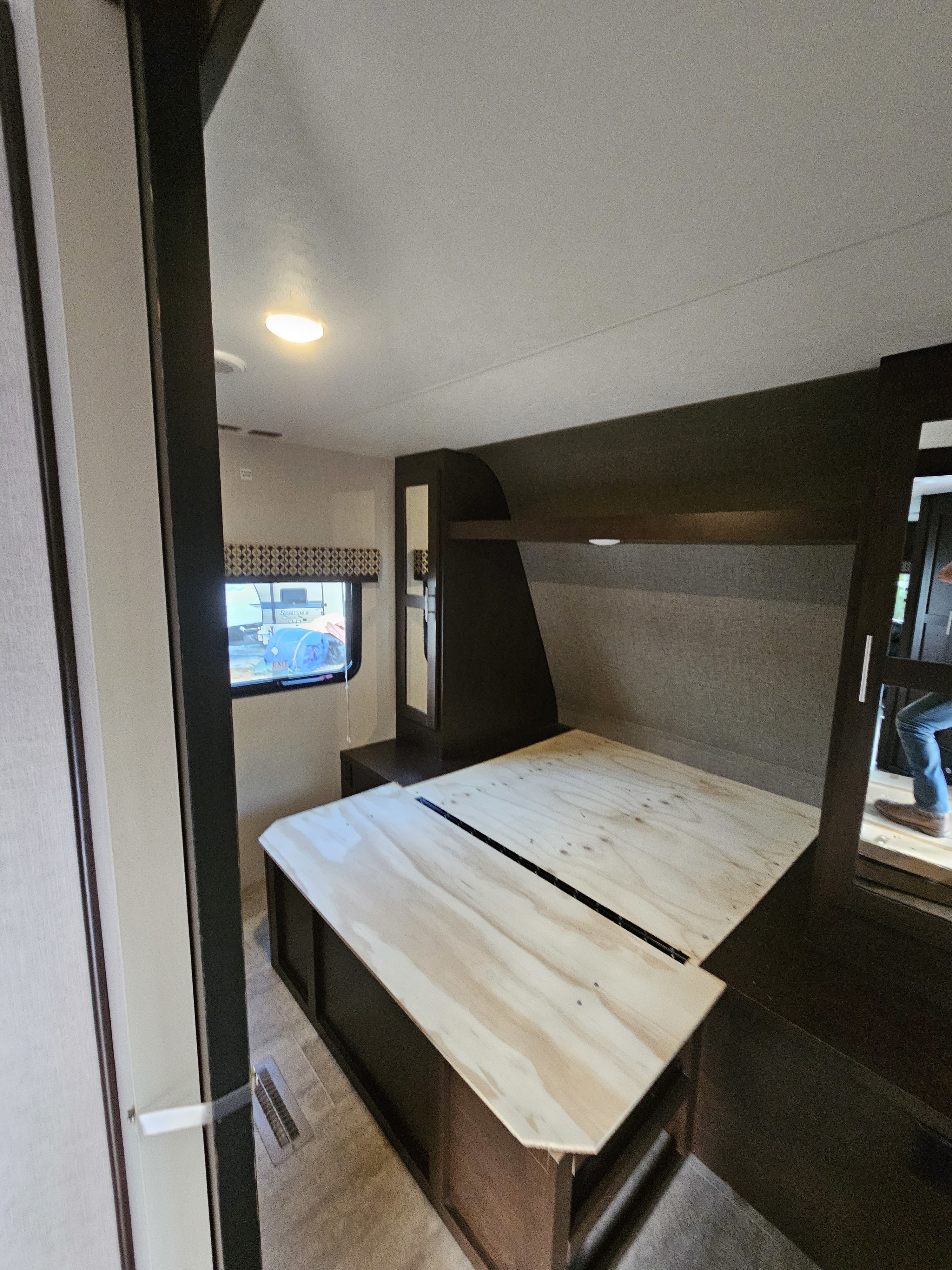RV rental bedroom featuring a wooden bed base and dark built-in storage units, ready for a mattress.. KZ Sportsmen 2018