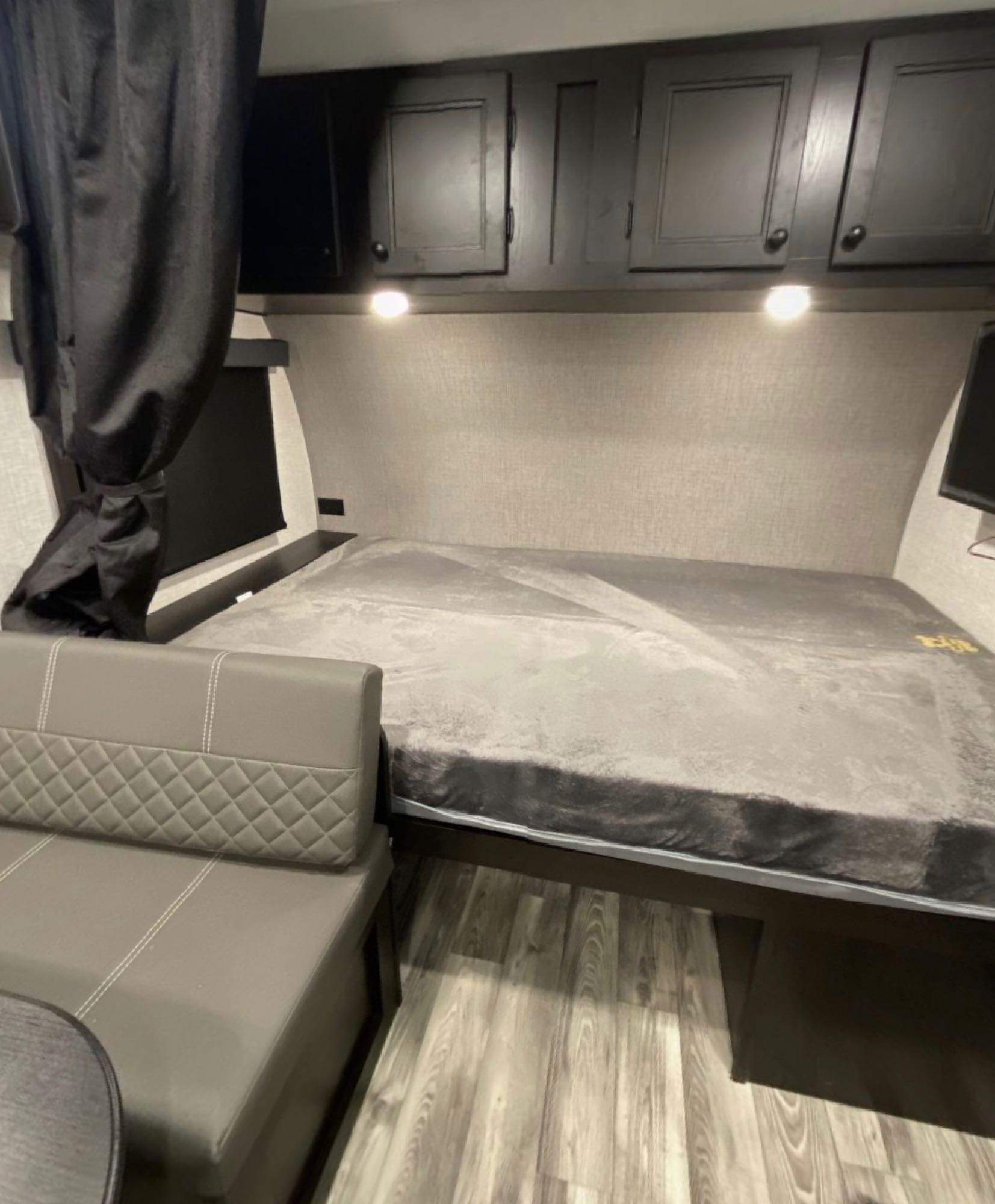 Inside this RV rental: a gray bed, dark overhead cabinets, cozy dinette, and wood-look floor.. Starcraft Super Lite Maxx 2022