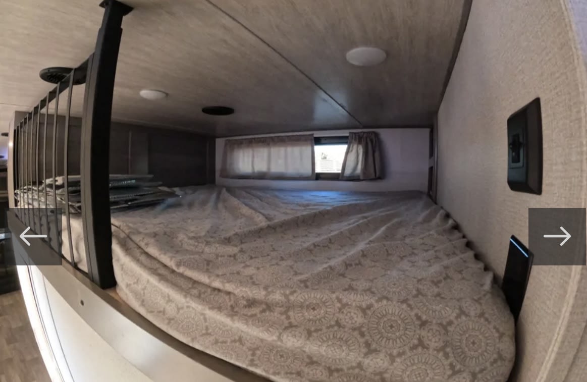 View of an RV rental sleeping loft with a bed, small window, and safety railing.. Keystone RV Montana 2021