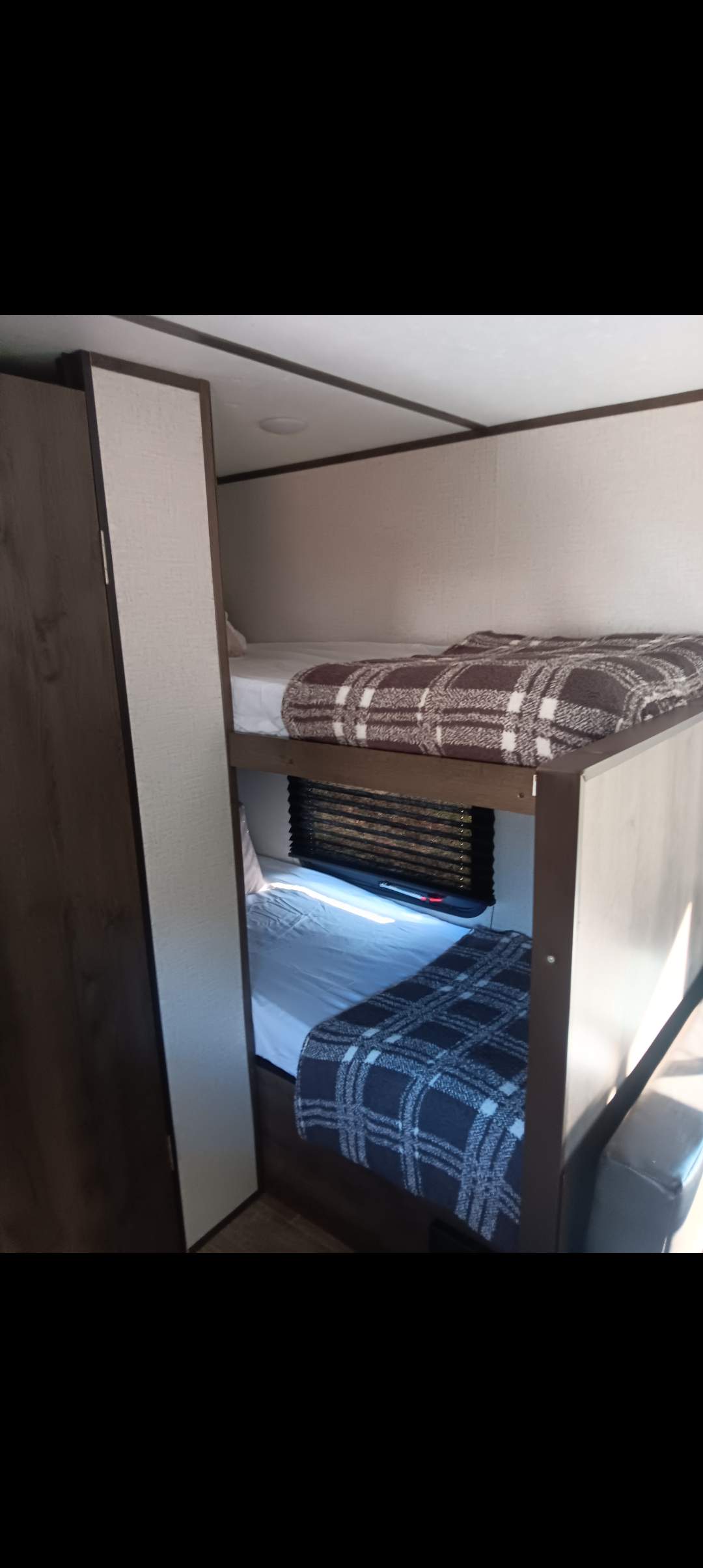 RV rental interior featuring two comfortable bunk beds with plaid blankets. Compact sleeping area perfect for families.. Dutchmen Coleman Lantern LT 2021