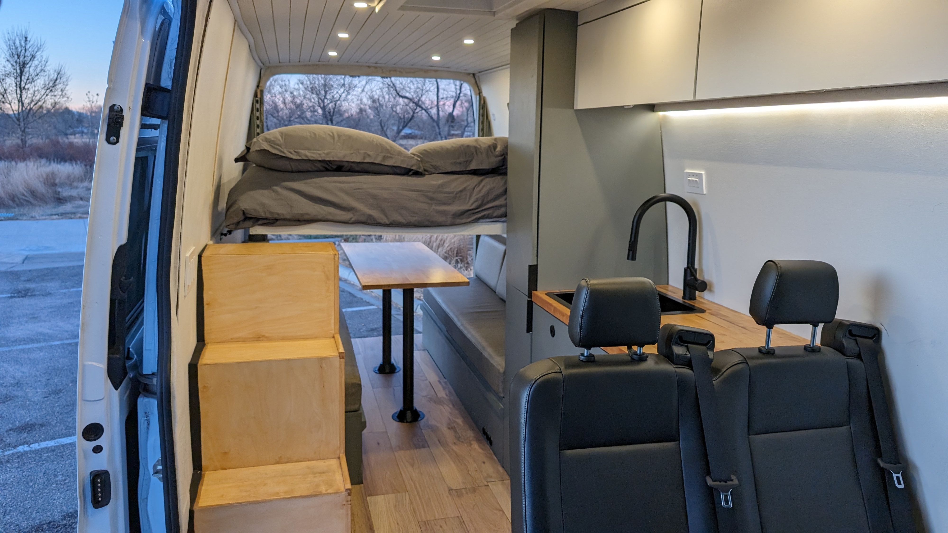 Explore this versatile RV rental interior featuring a cozy bed, compact kitchen, and dining area. Perfect for your next adventure!. Mercedes-Benz Sprinter 2020
