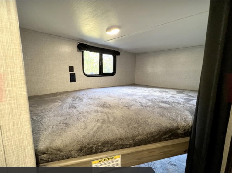Cozy RV rental bunk bed interior with a window, wall outlets, and a comfortable mattress for your next adventure.. Crossroads RV Zinger Lite 2022