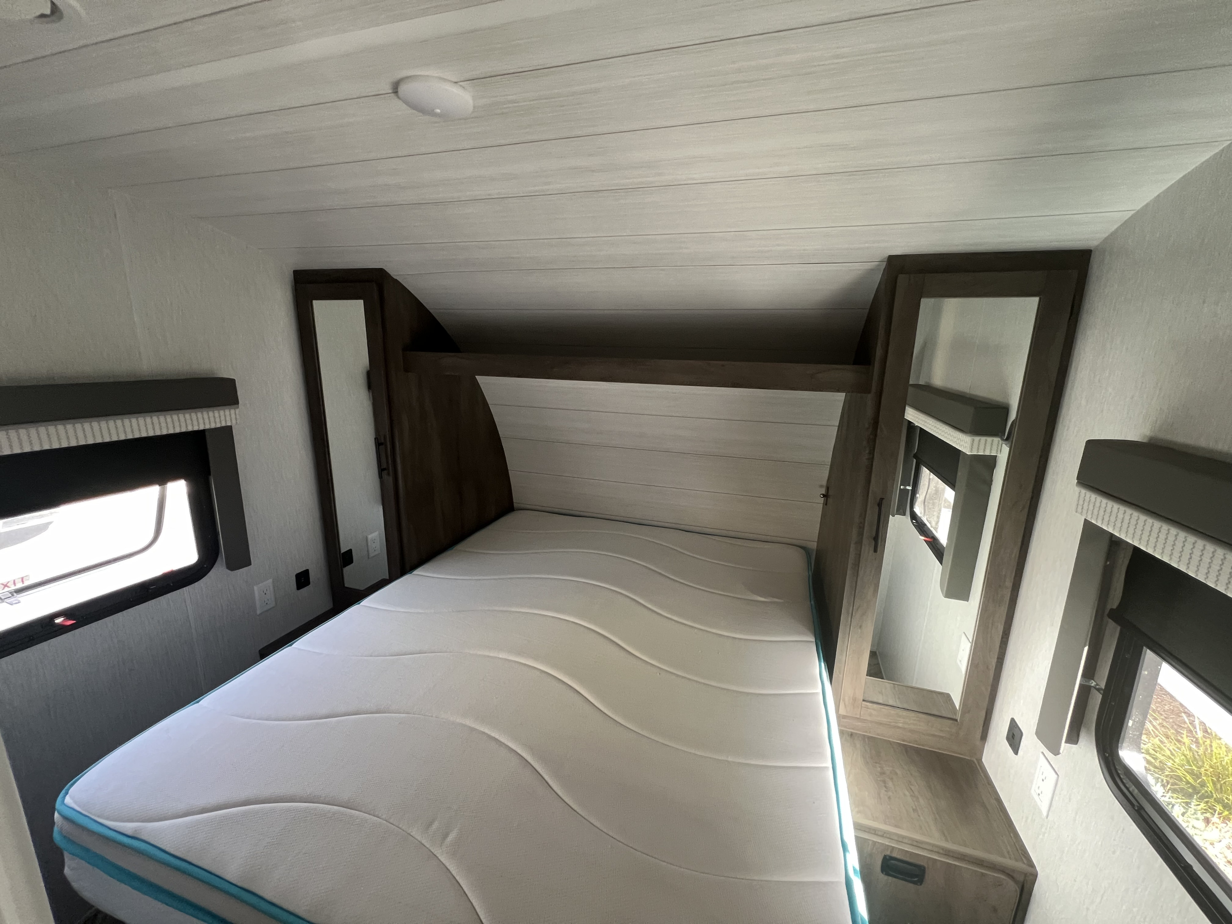 Comfortable RV rental bedroom: features a clean mattress, mirrored storage, and side windows for a bright interior.. Forest River Salem Cruise Lite 2022