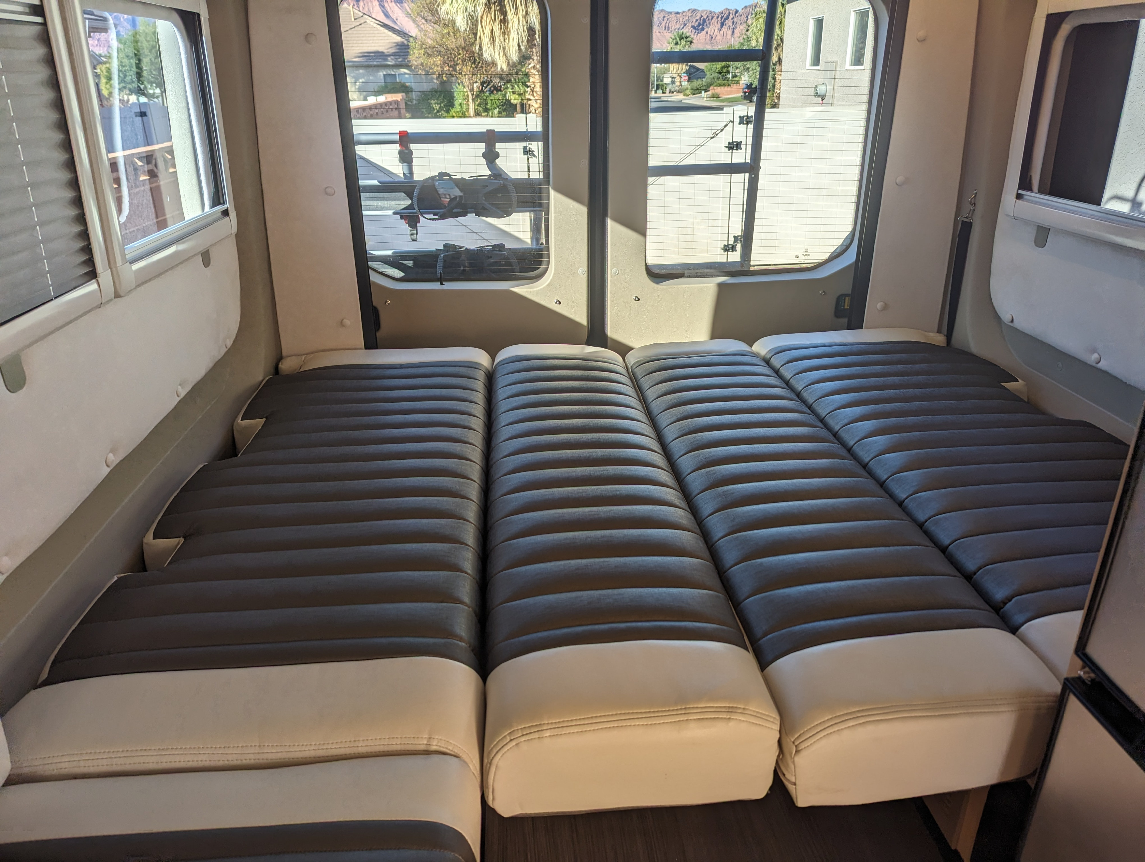 Spacious RV rental interior with comfortable modular bedding. Windows show desert mountains & outdoor rack.. Winnebago Paseo 2017