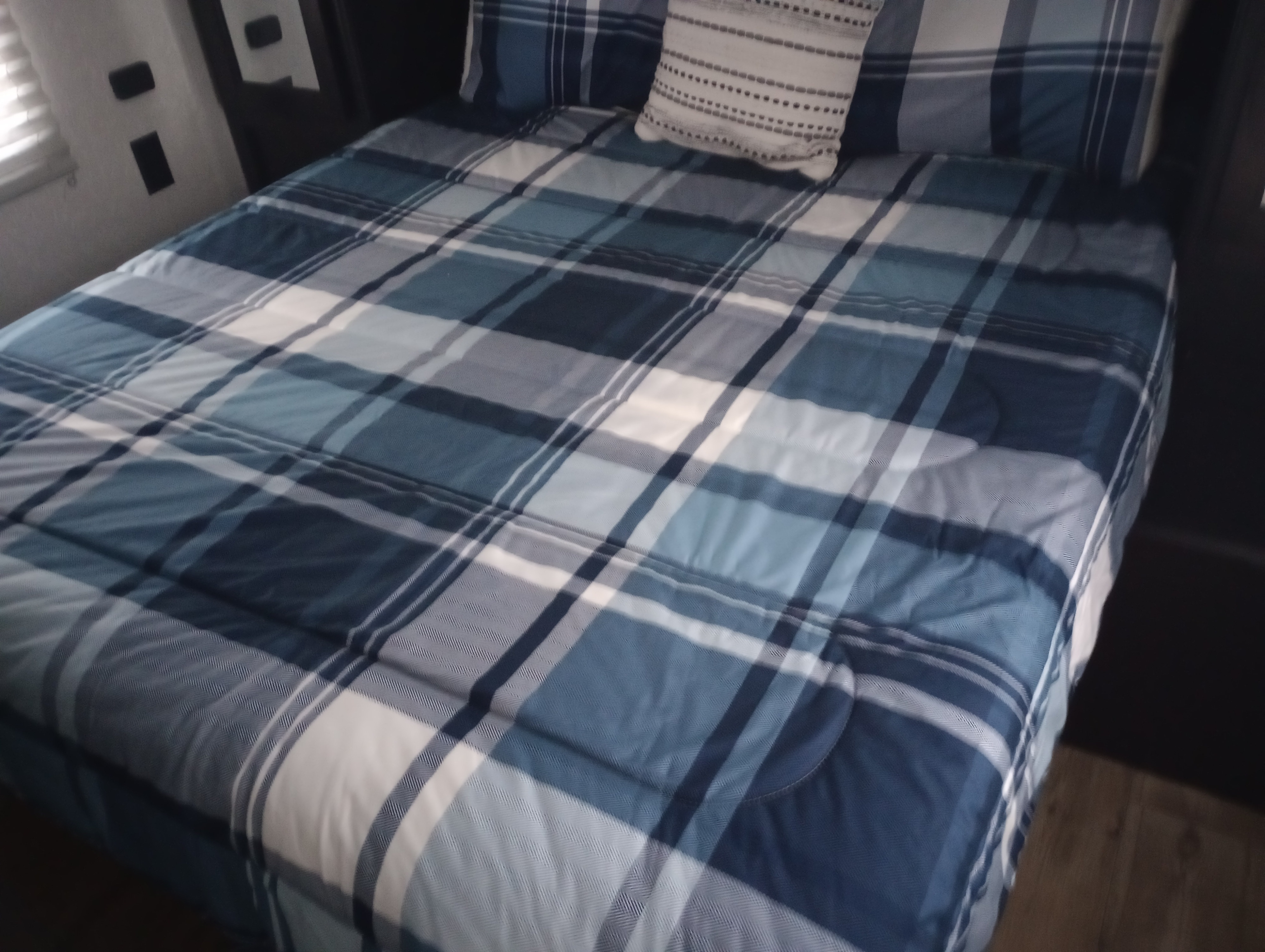 Cozy blue and white plaid bed in an RV rental bedroom, perfect for your next adventure.. Forest River Cherokee 2022