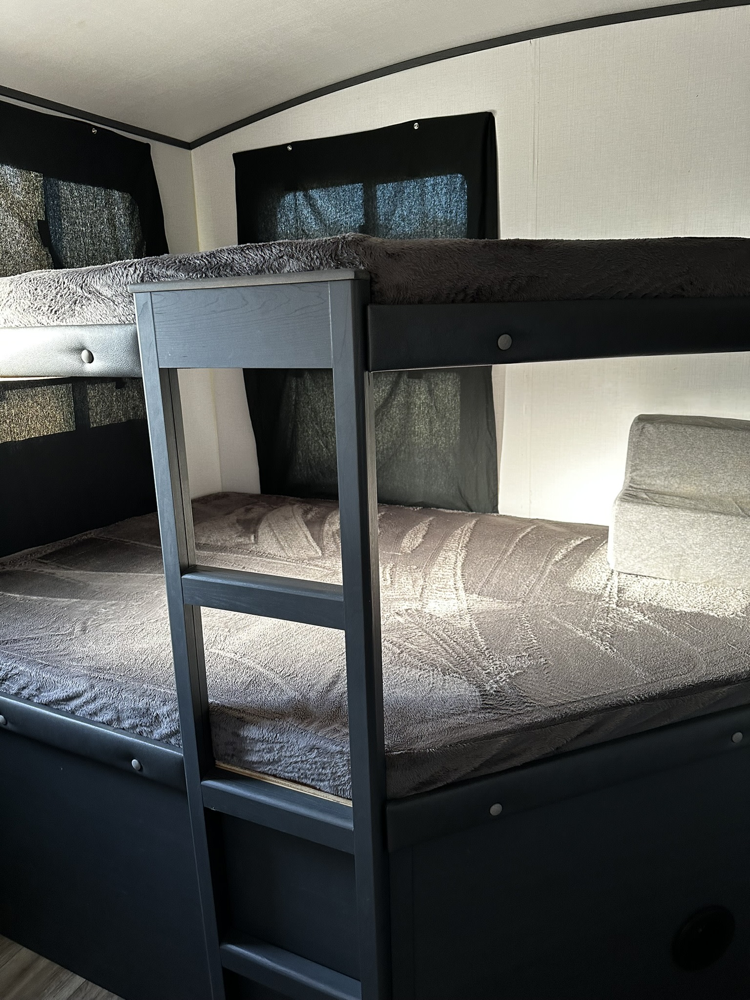 Cozy bunk beds in a modern RV rental, featuring soft gray blankets and dark frames. Ideal for family adventures.. Keystone RV Bullet Ultra Lite 2022