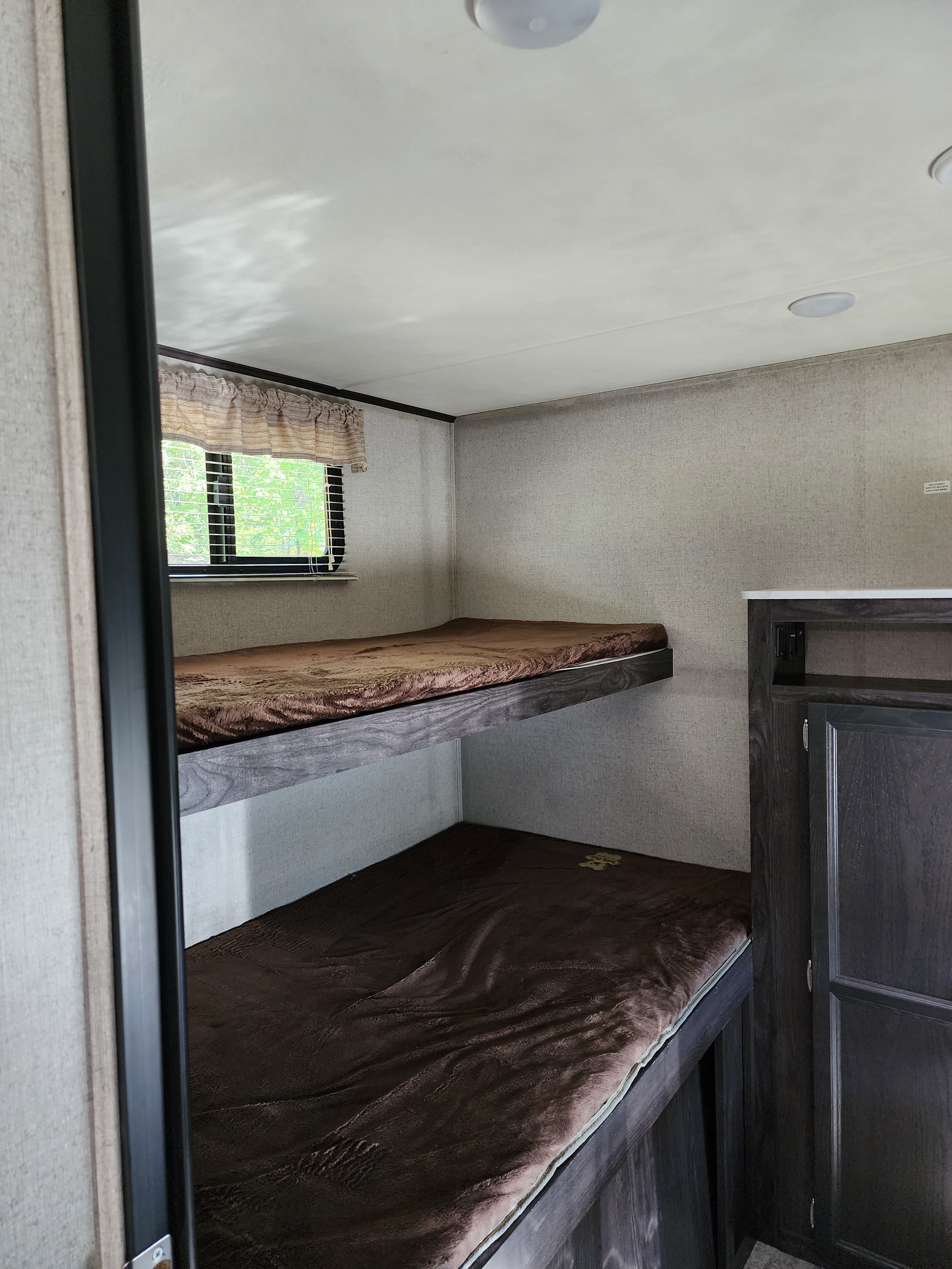 Inside an rv rental, these bunk beds offer a compact and functional sleeping area, complete with a window and nearby storage.. Dutchmen Kodiak Ultra Lite 2019