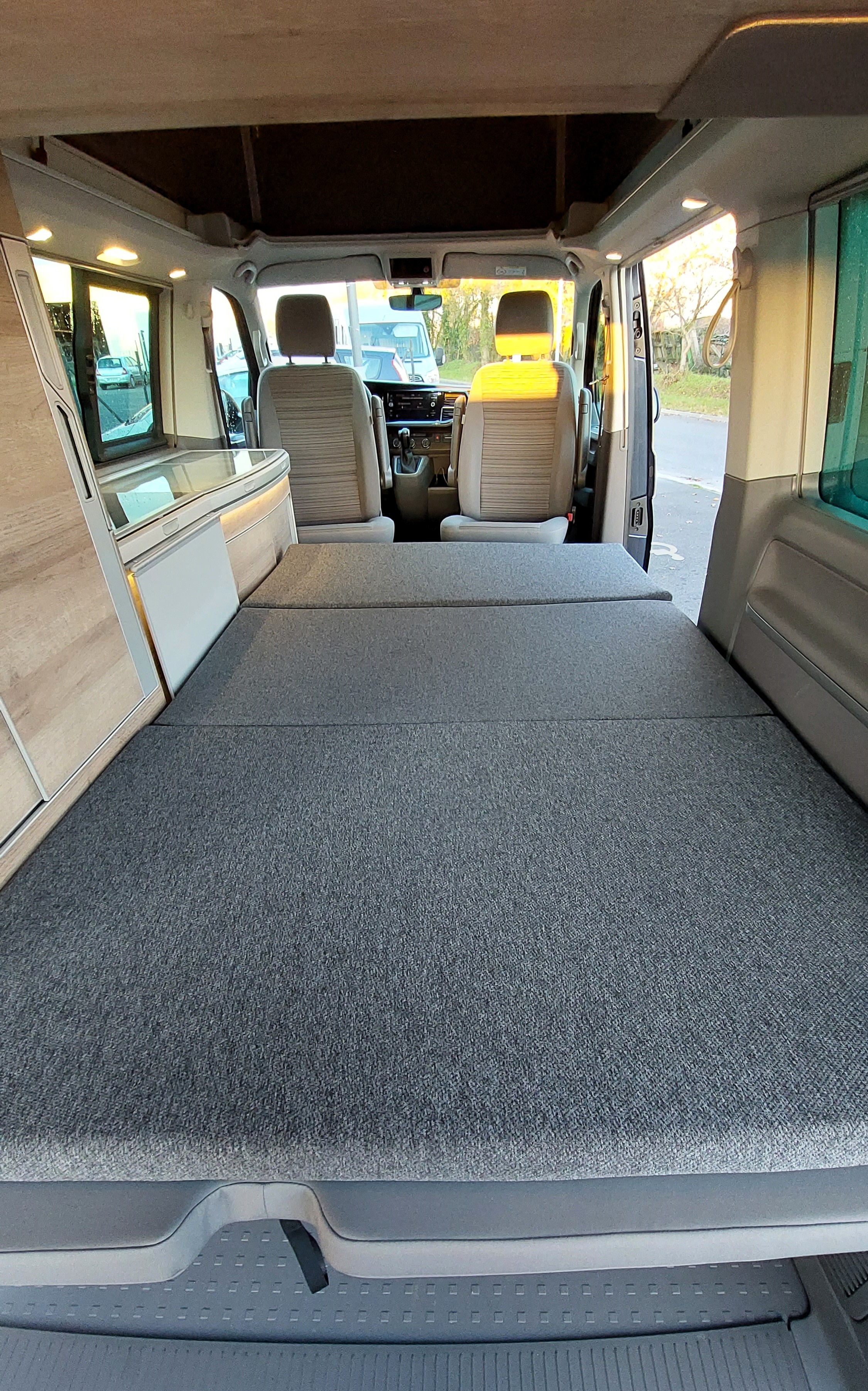 Cozy RV rental interior: bed, kitchenette, & front seats, ready for adventure in this versatile camper van.. Volkswagen CALIFORNIA COAST 2021