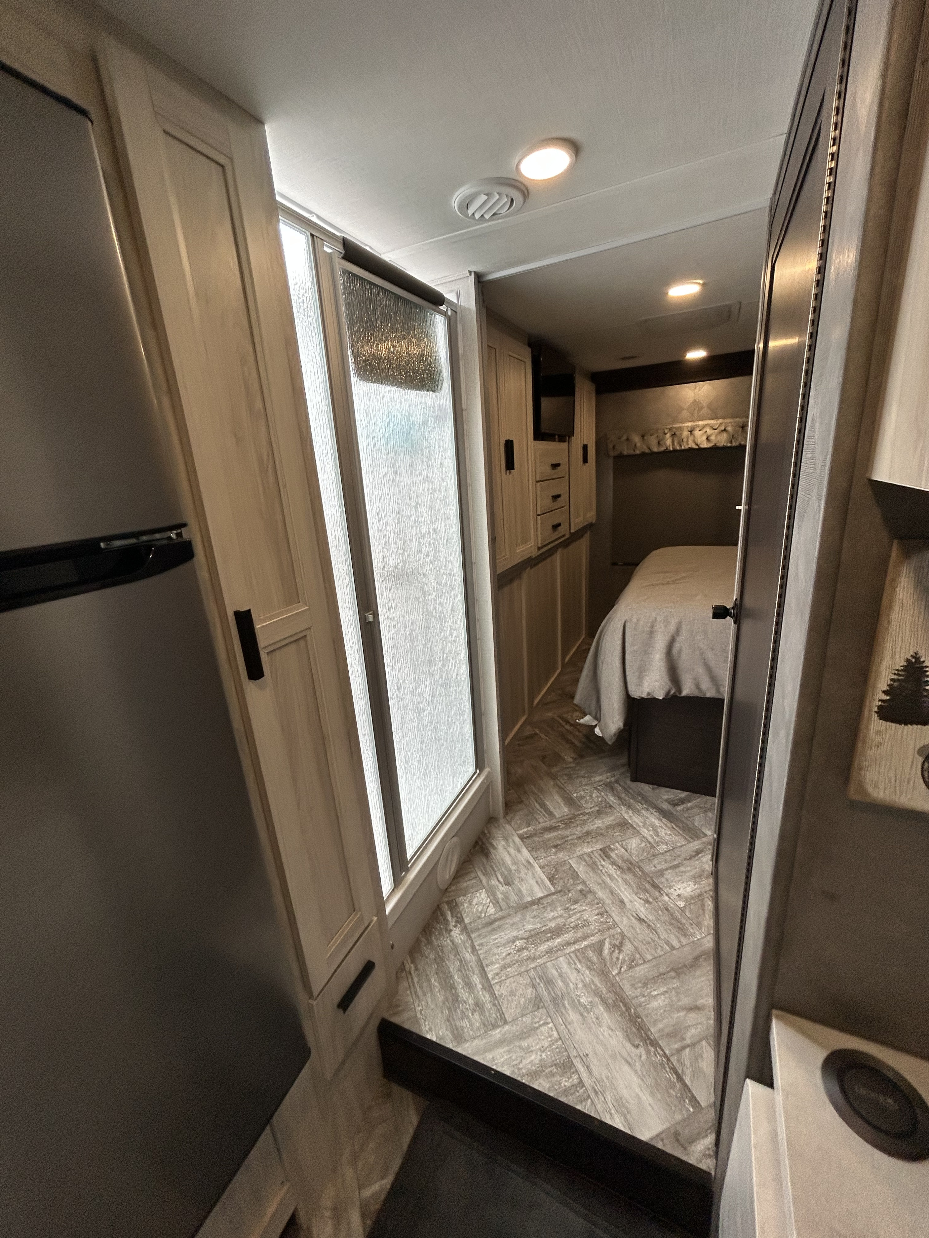 Step inside this RV rental! View of the interior from the entry, revealing the kitchen fridge, shower stall, and a bedroom beyond.. Forest River Sunseeker Classic 2022