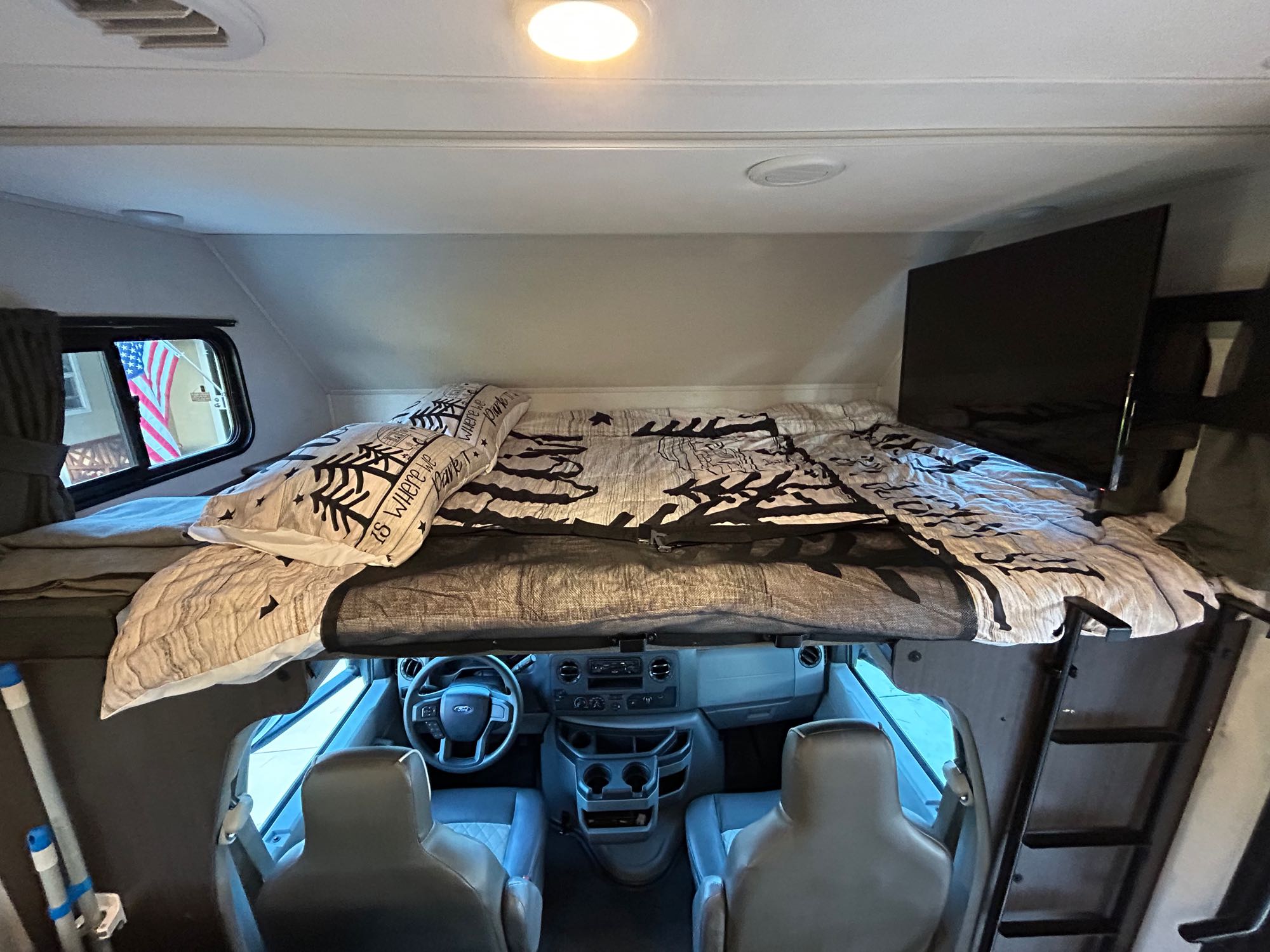 Cozy RV rental interior with an over-cab bunk bed, front cockpit, and TV. Perfect for travel adventures!. Forest River Sunseeker LE 2022