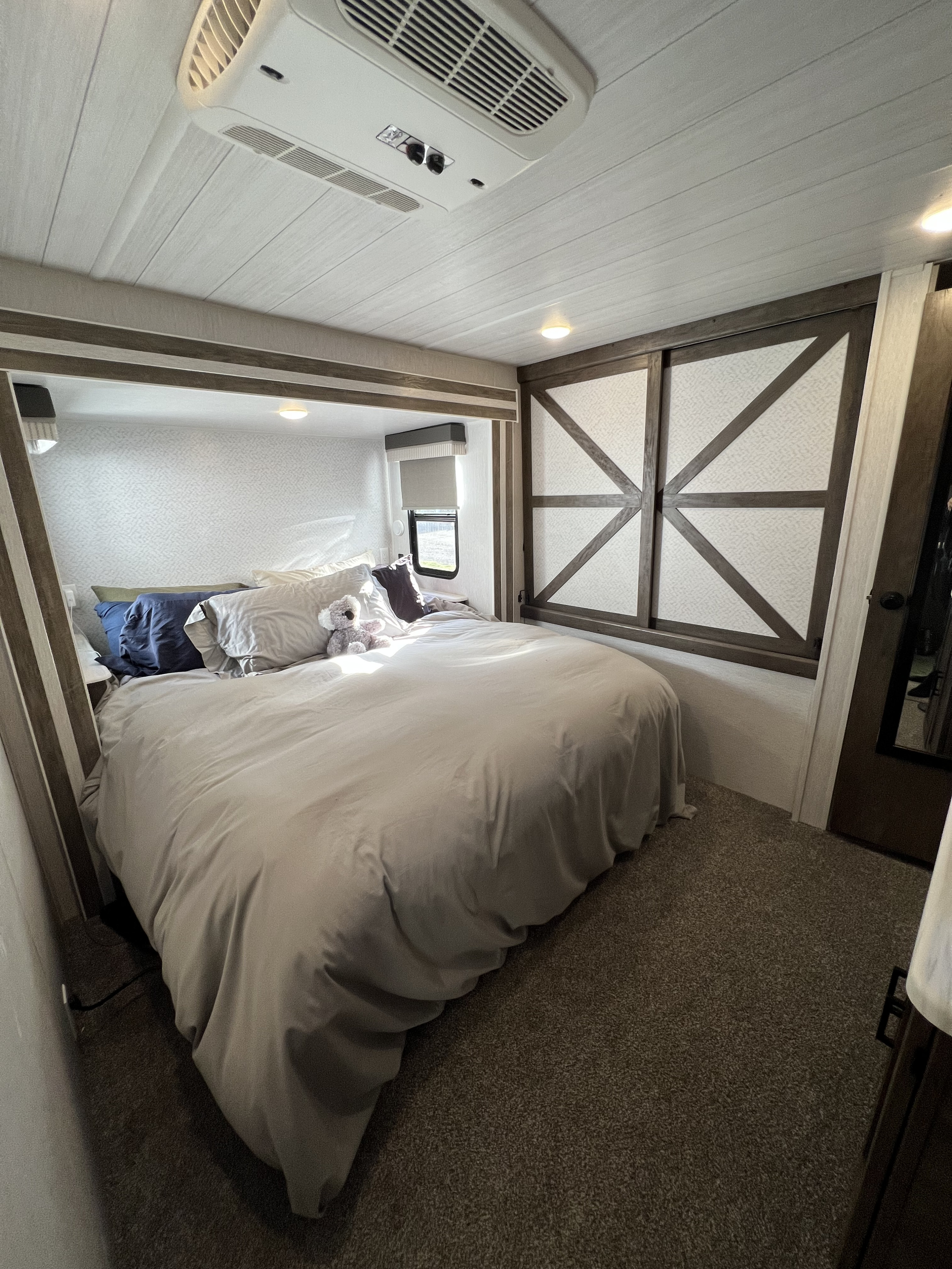 This cozy RV rental bedroom features a comfy bed, modern AC, textured ceiling, and stylish built-in storage.. Forest River Salem 2022