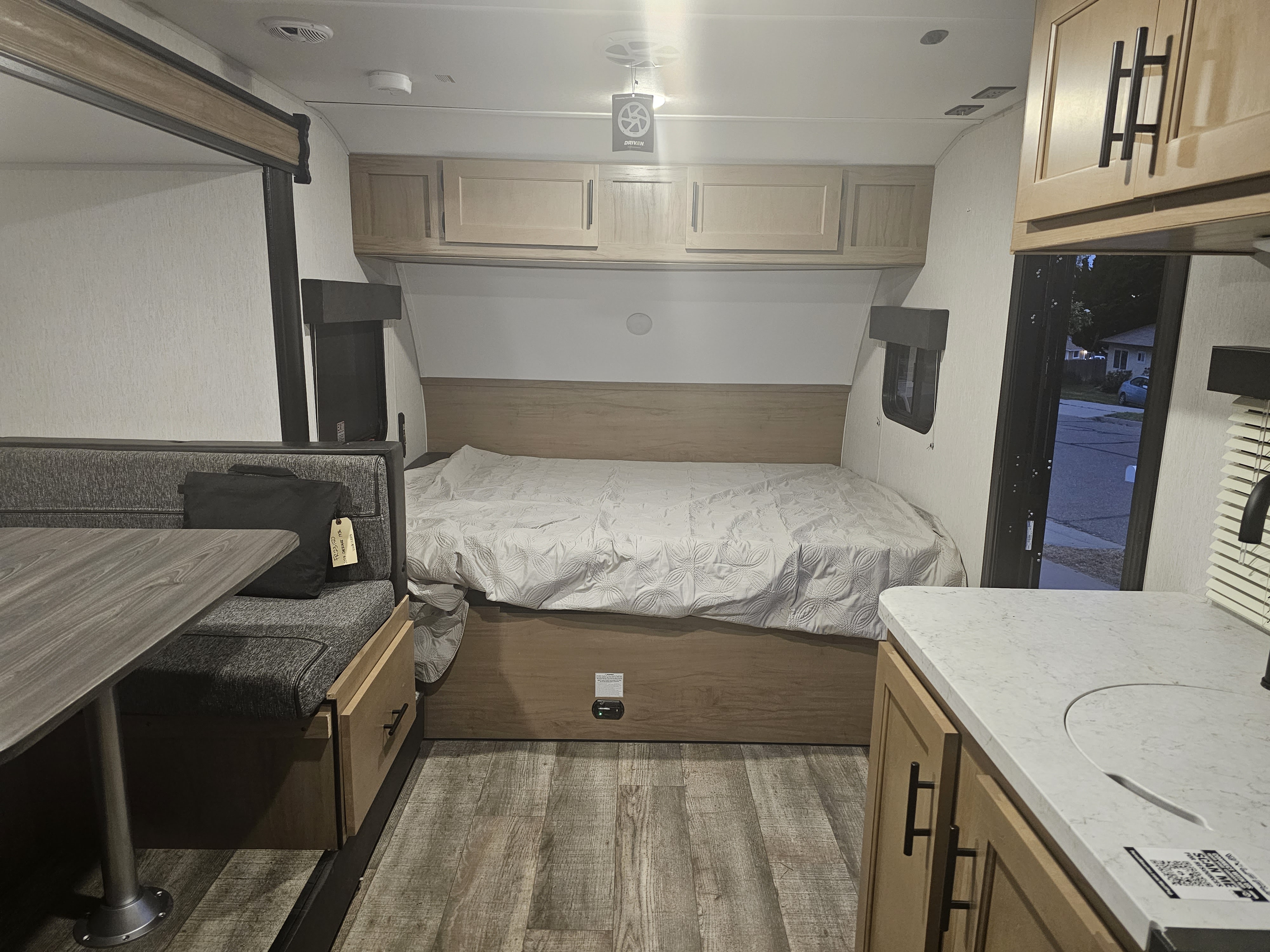 Inside an RV rental, showing the cozy bed, dining area with table, and compact kitchen space.. Forest River Cherokee Wolf Pup 2023