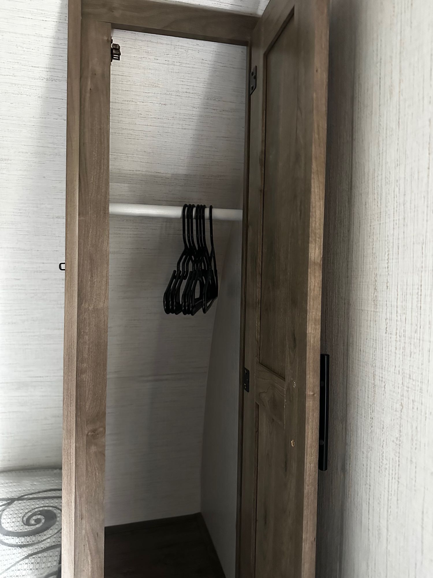 RV rental interior: an open wooden closet with a hanging rod and black hangers, offering practical storage space.. Heartland RVs Pioneer 2024