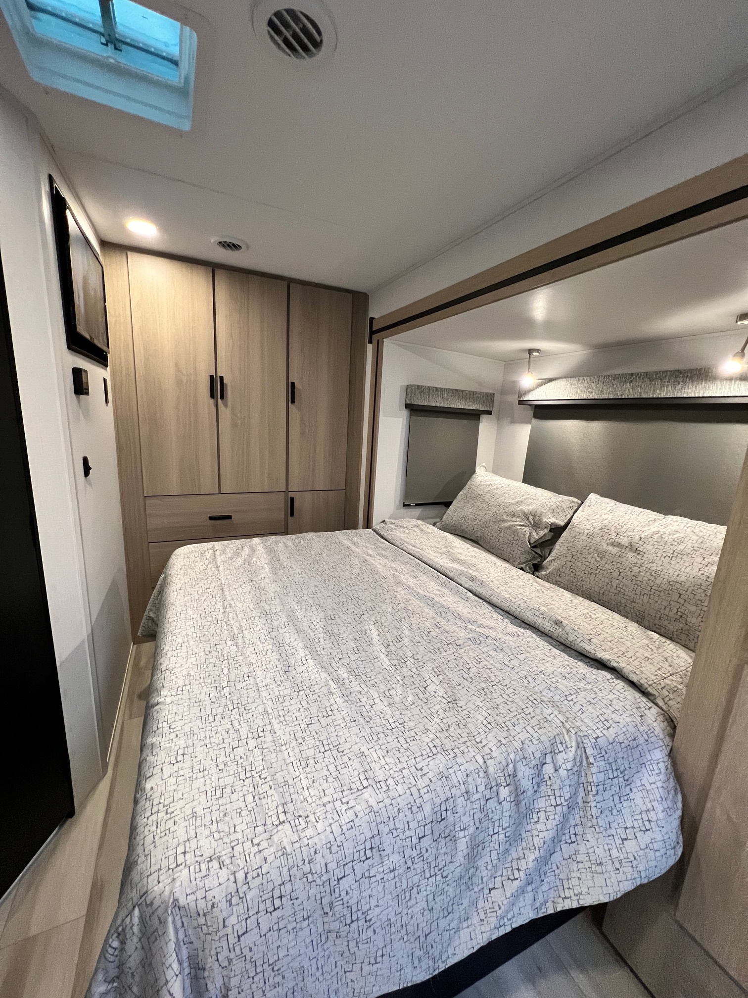 Cozy RV rental bedroom with patterned bedding, built-in storage, and modern lighting. Experience comfort on the road.. Forest River Sunseeker 2024