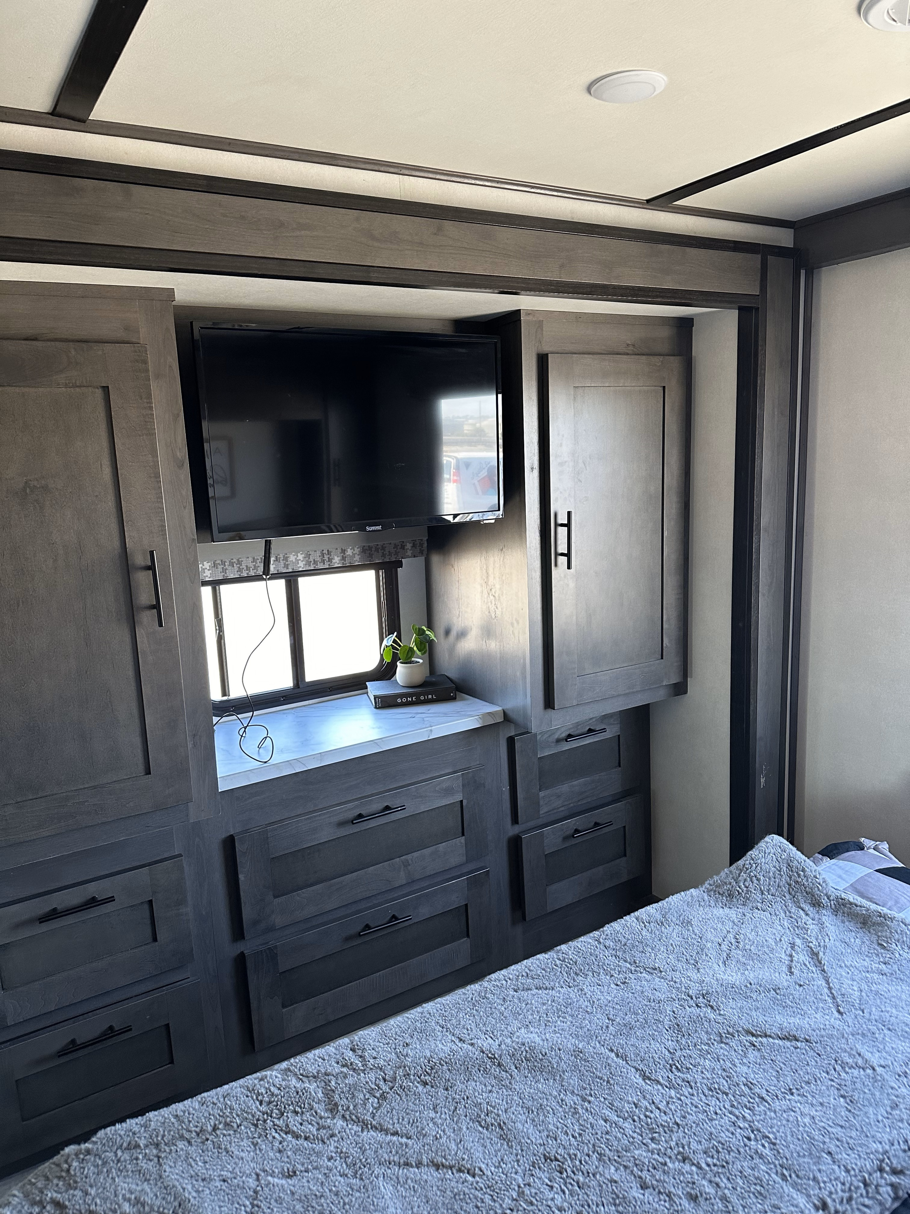 RV rental bedroom interior with dark wood storage, TV, and cozy blanket. Perfect for a comfortable stay.. FR3 FR3 Motorhome 2021