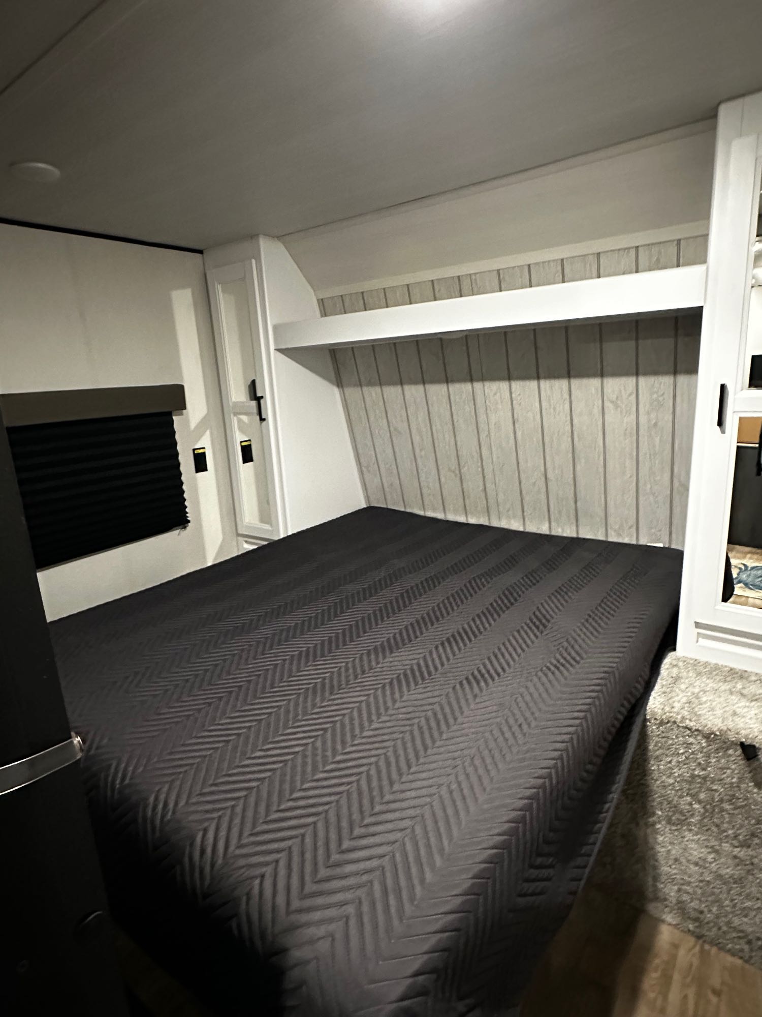 This compact RV rental bedroom offers a comfortable bed, practical overhead storage, and light wood paneling for travel.. Keystone RV Hideout 2022