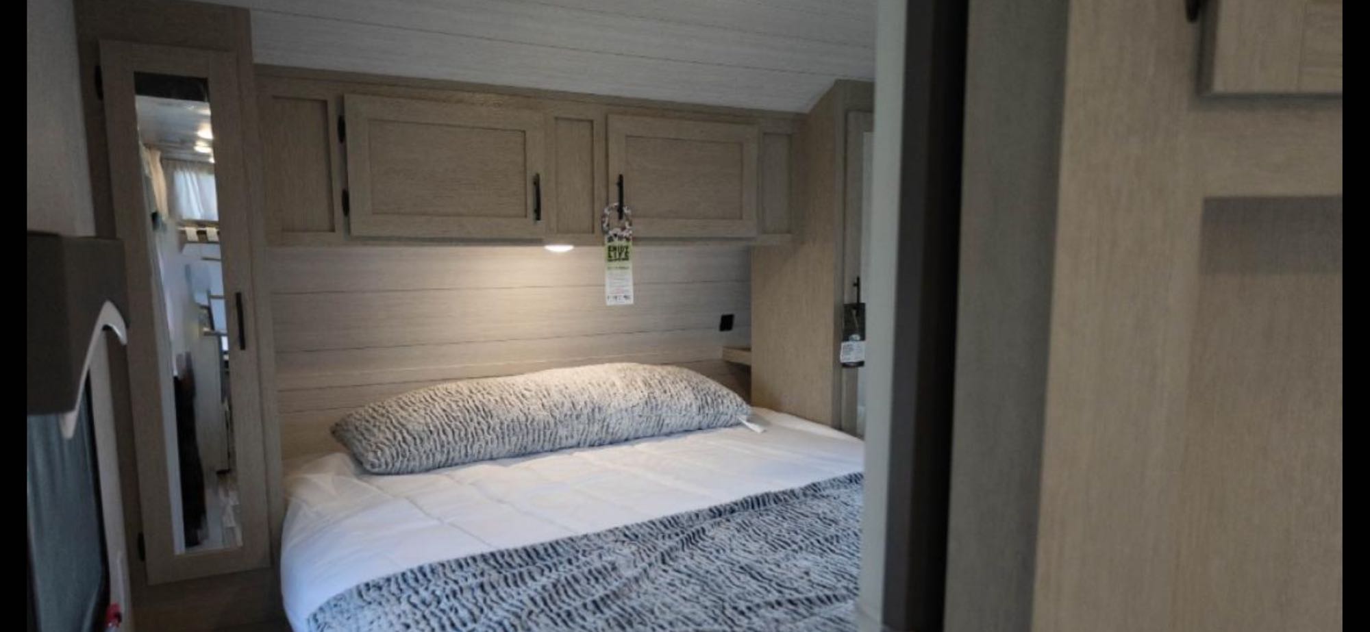 Cozy RV rental bedroom featuring a comfortable bed, light wood walls, and practical overhead cabinets. Includes a full-length mirror.. Forest River Evo 2650 2023