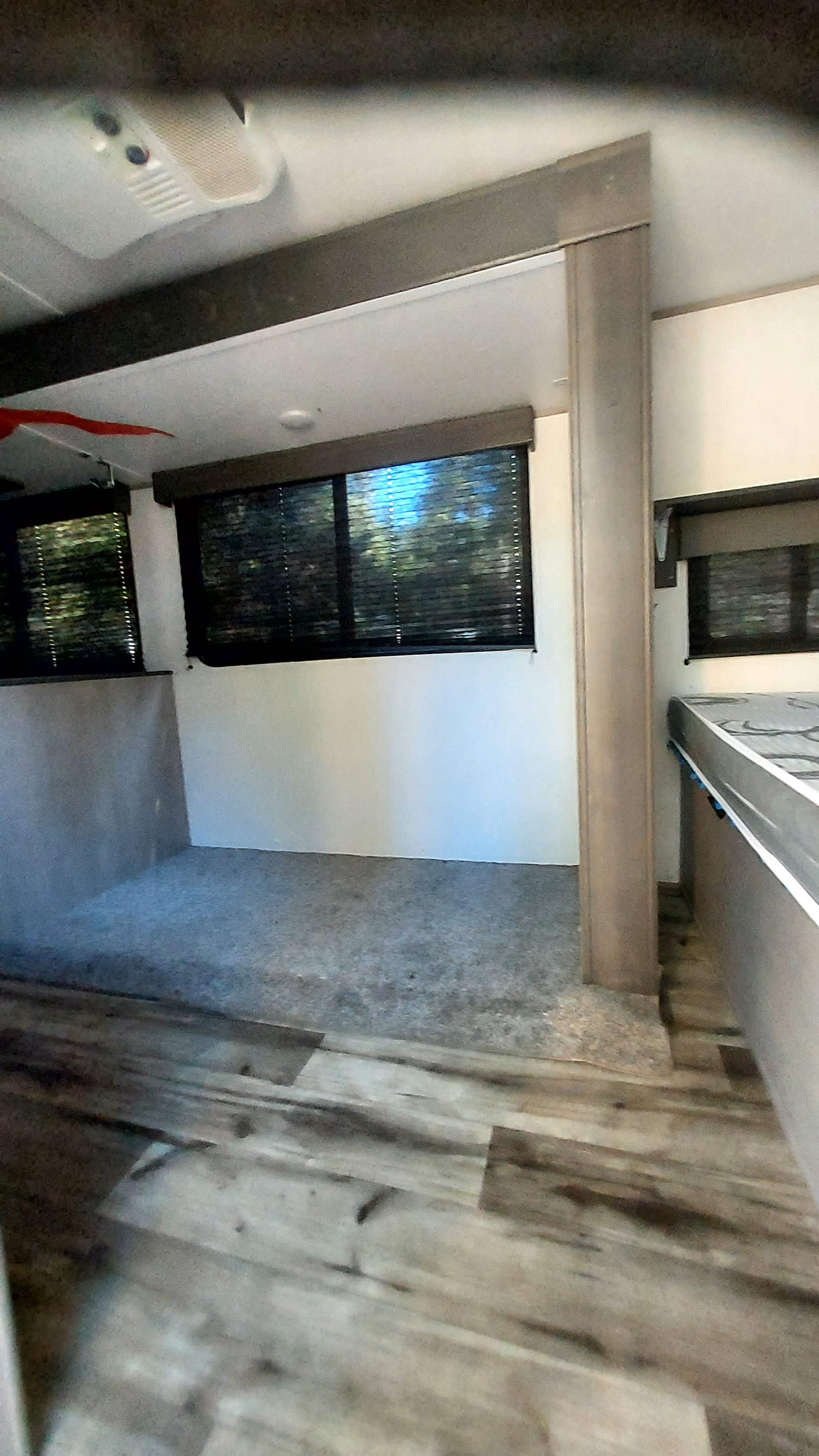 Clean RV rental interior: wood-look floor, window blinds, and versatile living/sleeping area.. Dutchmen Coleman Lantern LT 2023